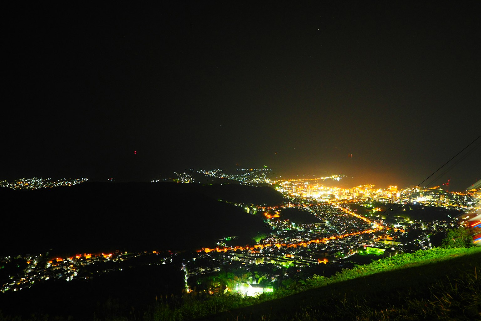 Pemandangan panorama kota di malam hari dengan cahaya cerah dan latar hijau