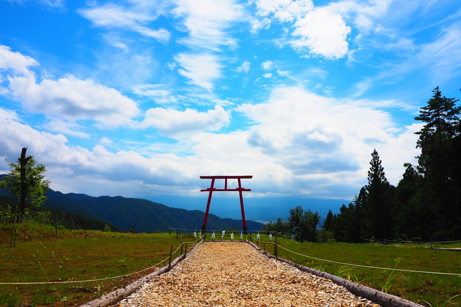 Weg zu einem roten Torii mit Bergen und blauem Himmel