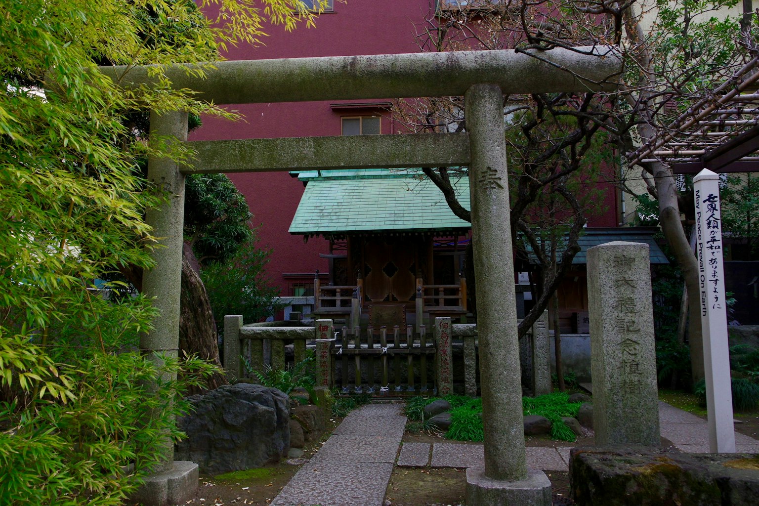Puerta torii de piedra rodeada de vegetación con un pequeño santuario