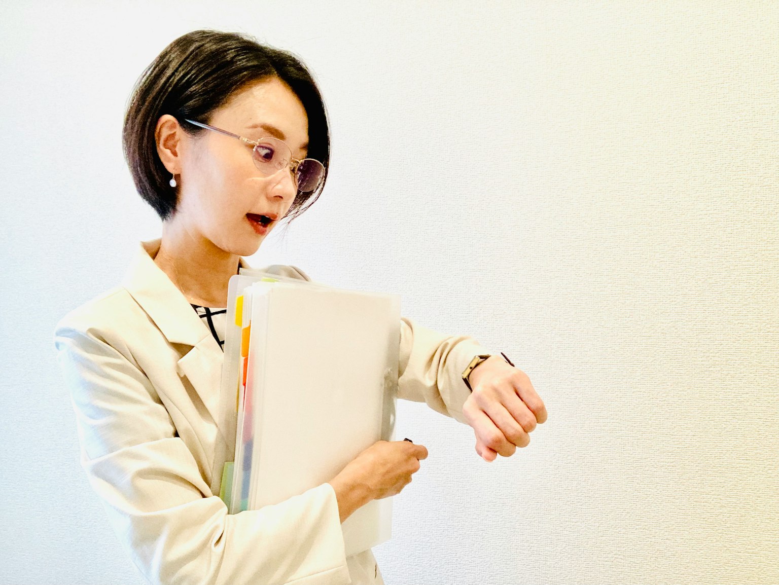 A woman in a white suit looking at her wristwatch