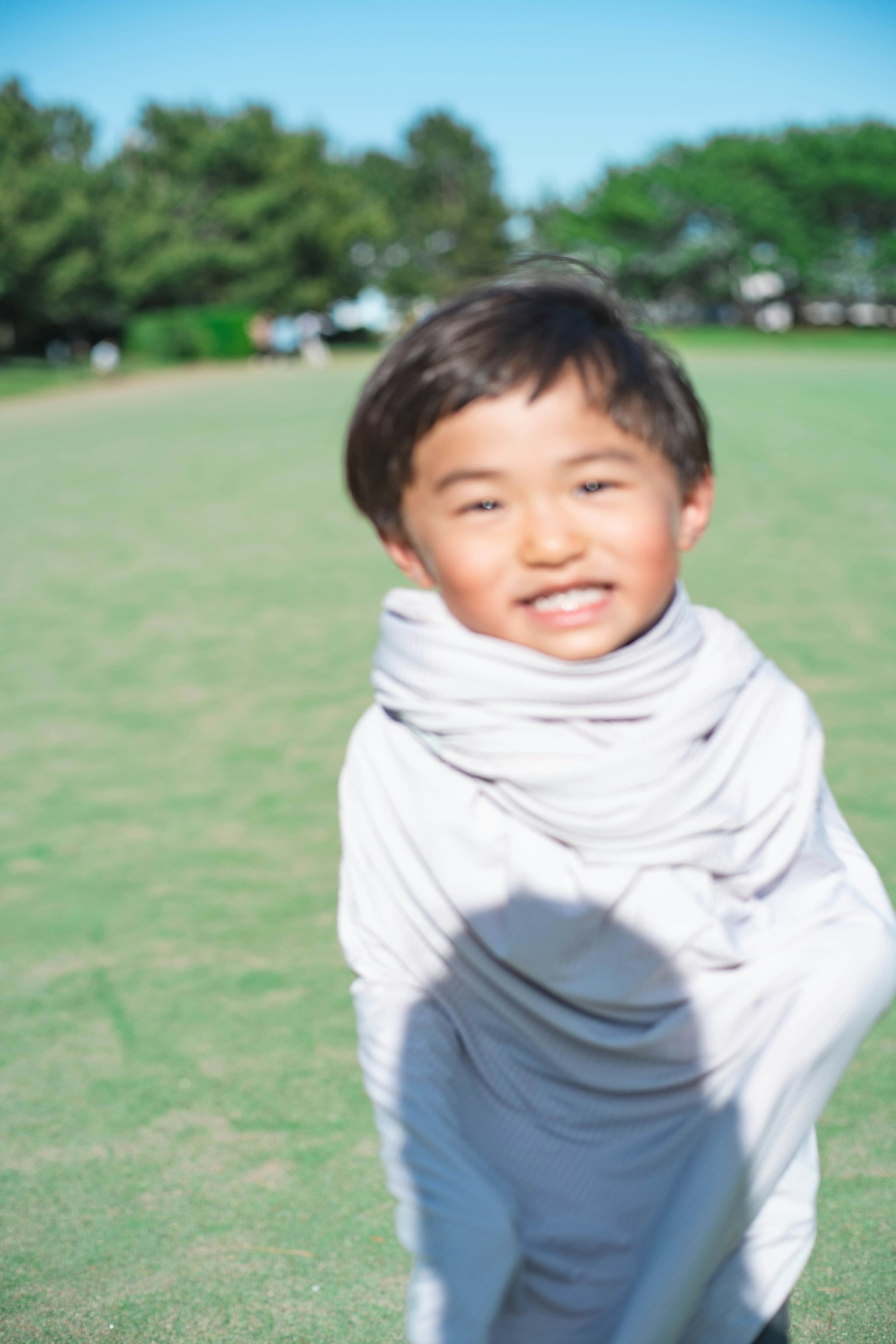 Smiling boy wrapped in white fabric playing in a park
