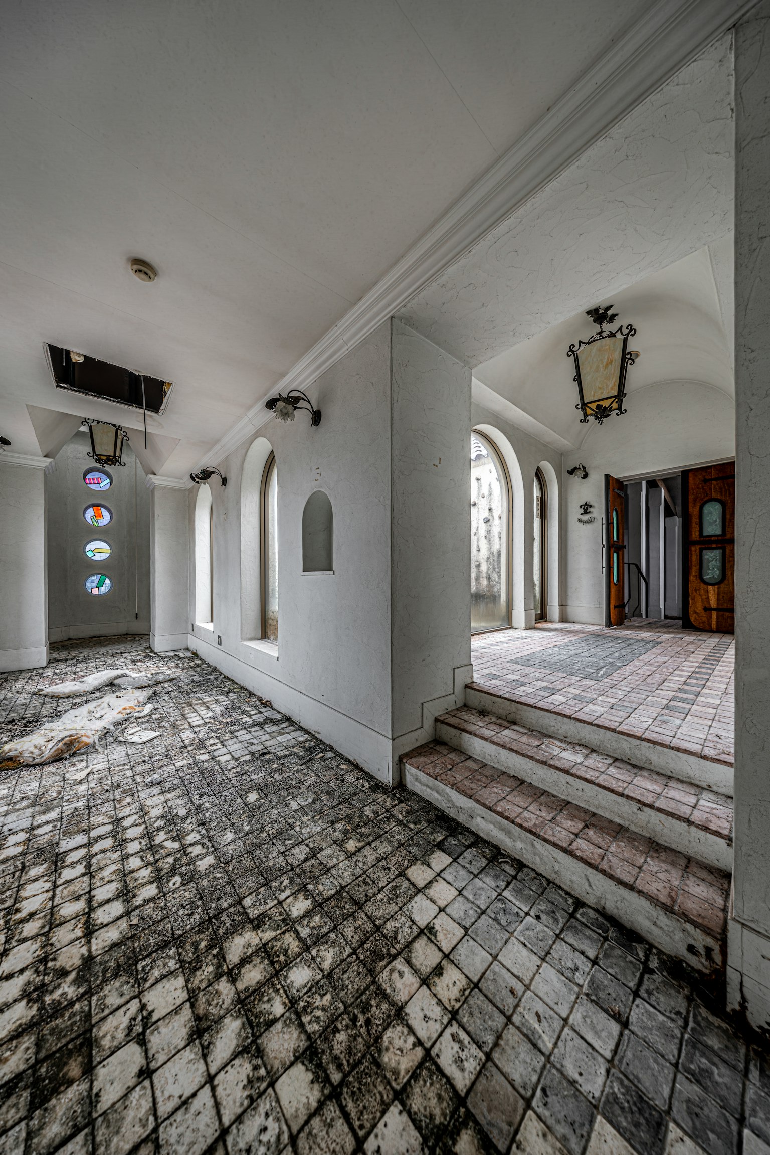 Pasillo interior de un edificio antiguo con ventanas decorativas y lámparas