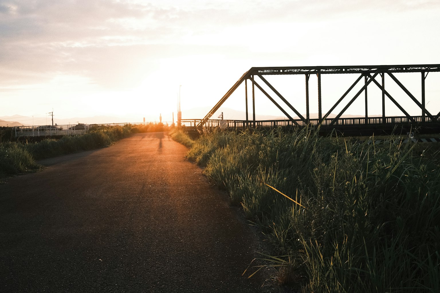 Vista del atardecer con un camino y un puente de metal