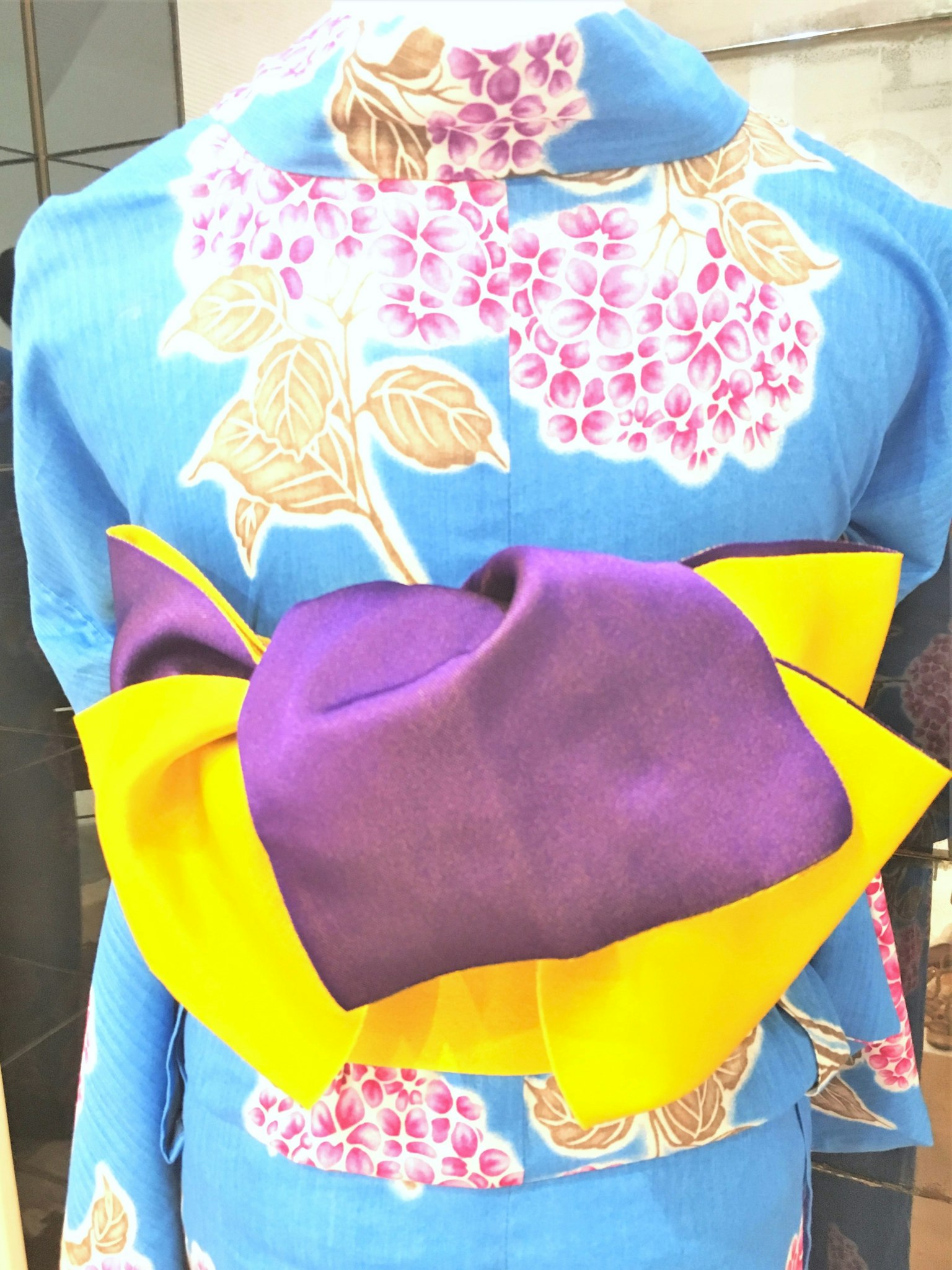 Kimono biru dengan pola bunga dan obi ungu dan kuning