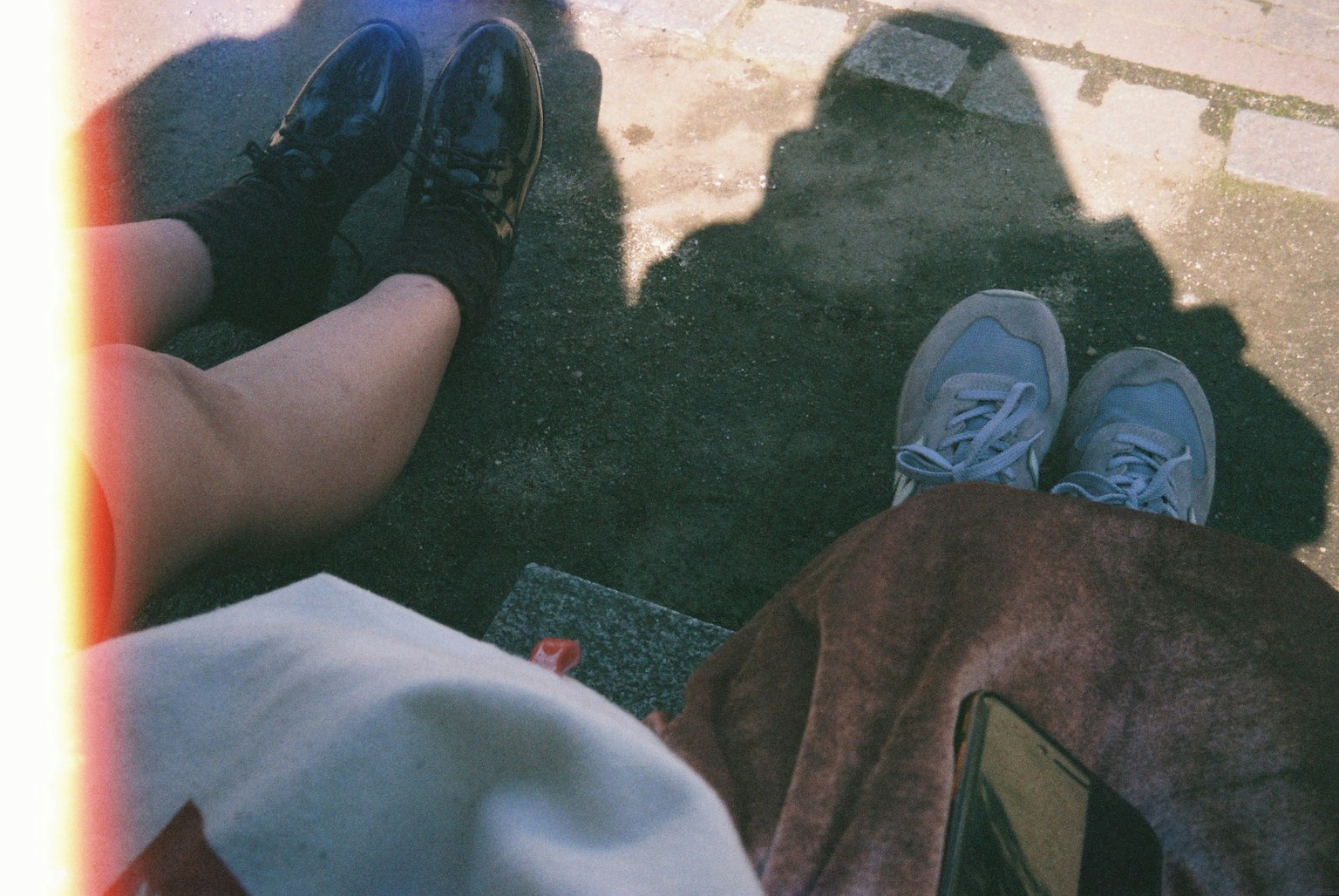Photo montrant deux paires de pieds l'une en chaussures noires et l'autre en baskets bleues