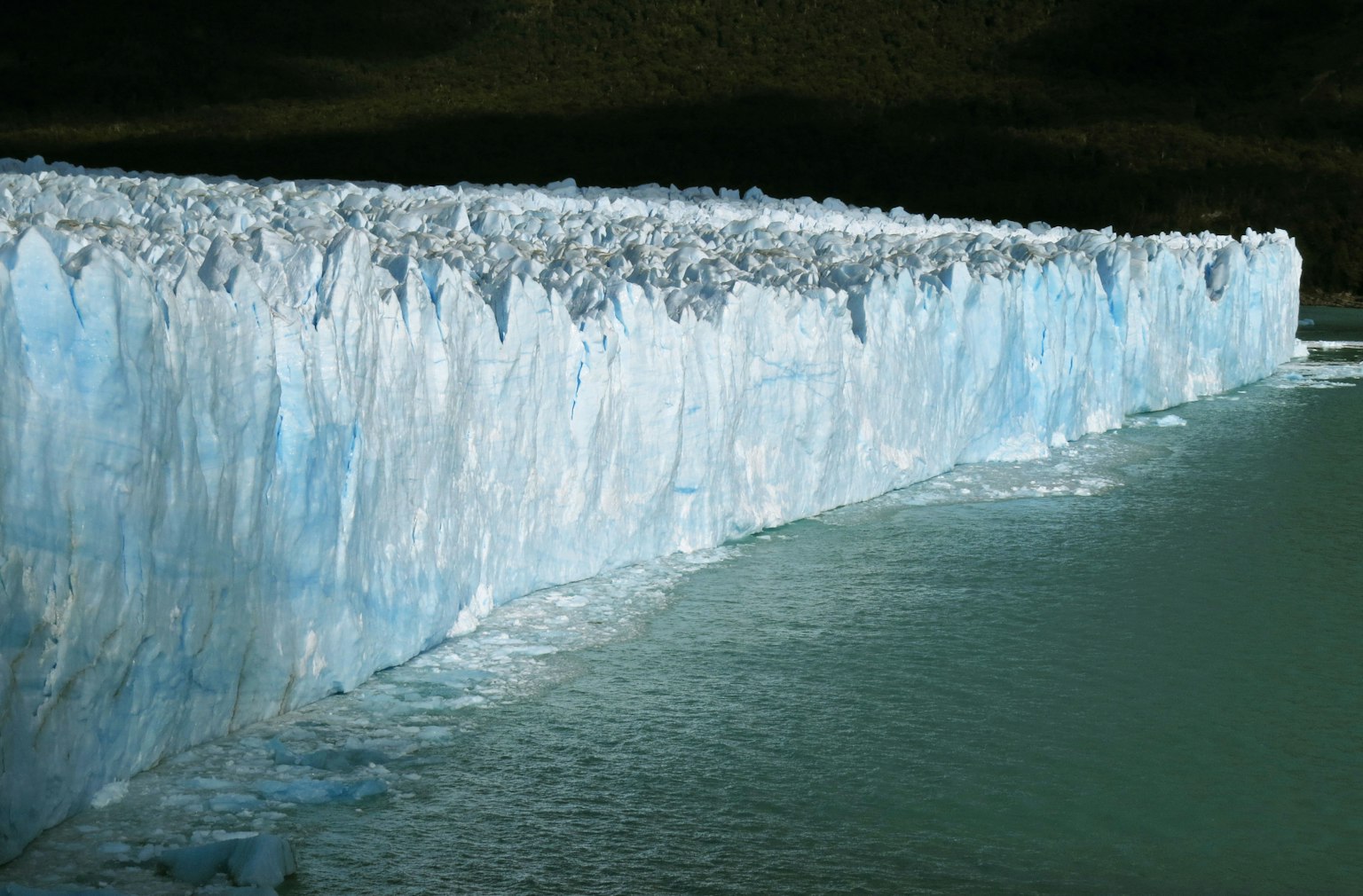 Muraglia di ghiaccio con sfumature di blu e superficie d'acqua