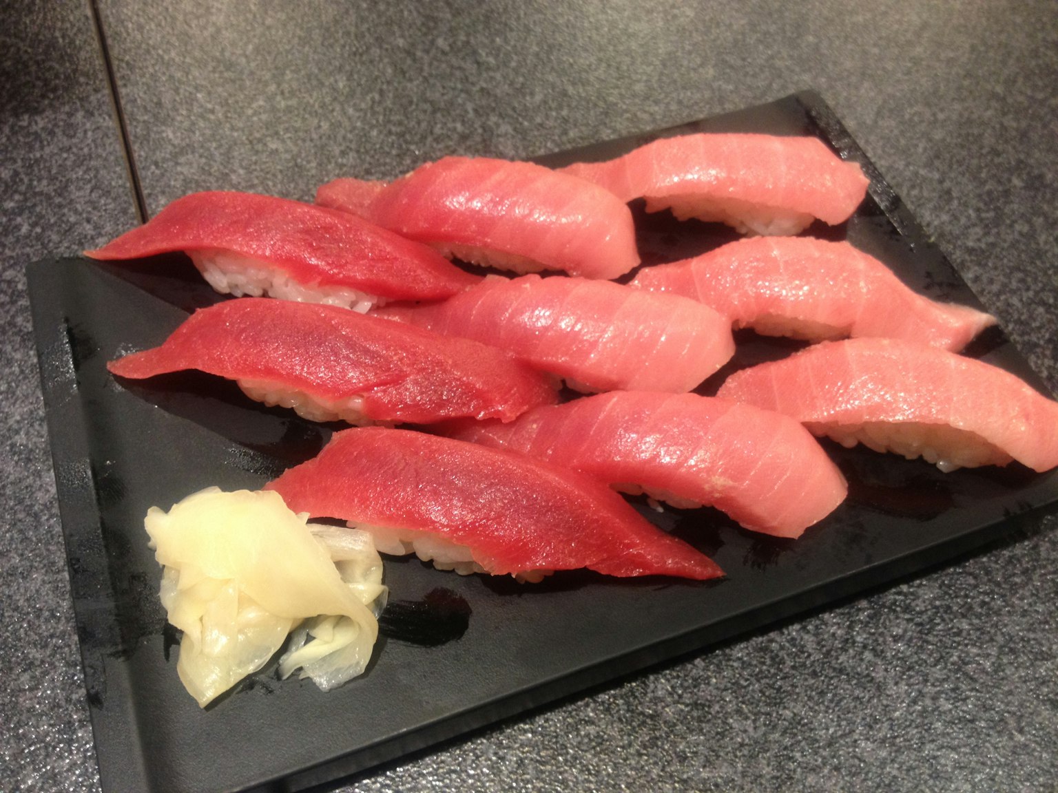 Asortimen sushi di atas piring hitam