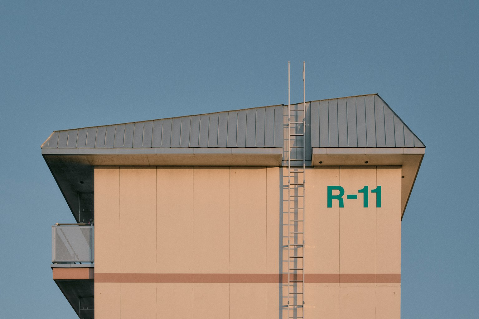 Un alto edificio con il tetto con R-11 scritto e una scala attaccata