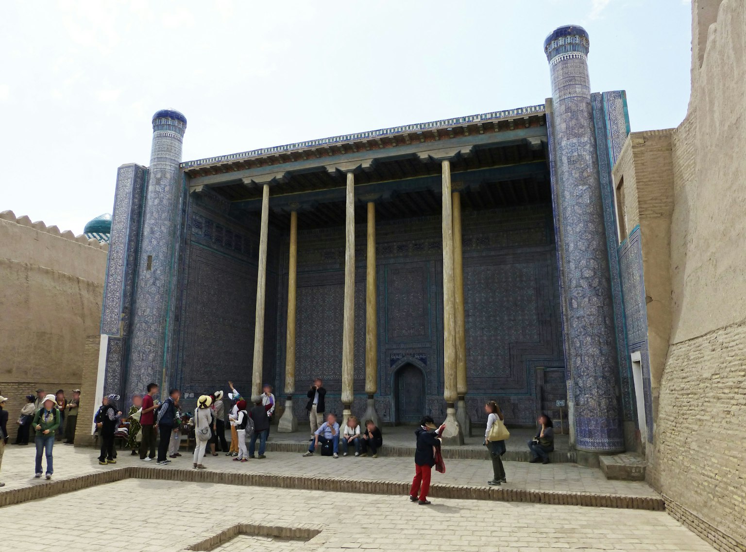 Ancient building with tall columns and people gathering in the courtyard