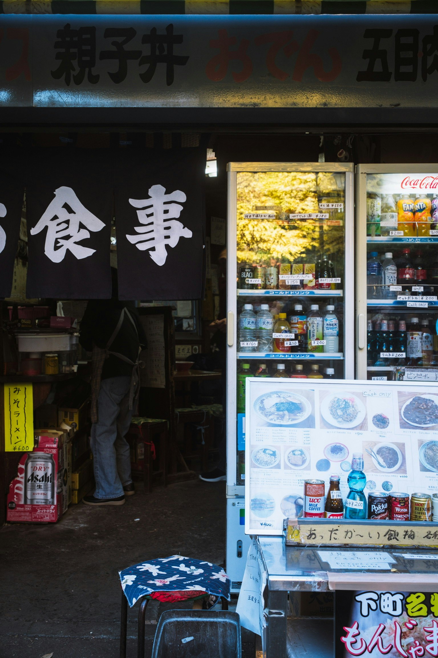 餐飲場所外觀的圖像，黑色招牌上有白色字樣，冰箱展示飲料和食物