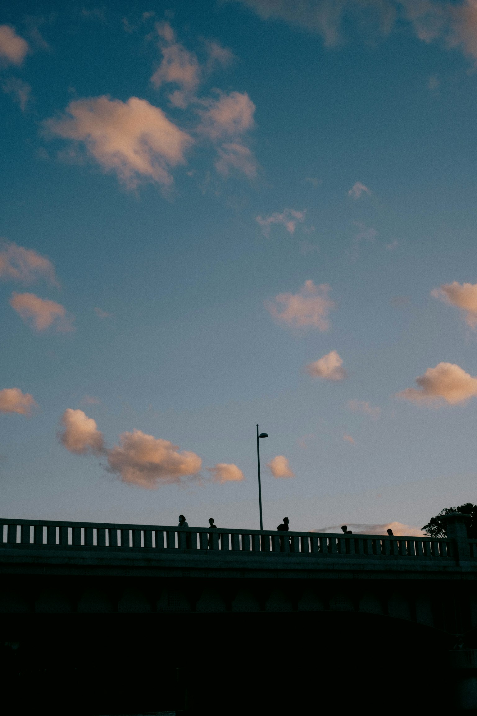 Silueta de un puente contra un cielo azul con nubes