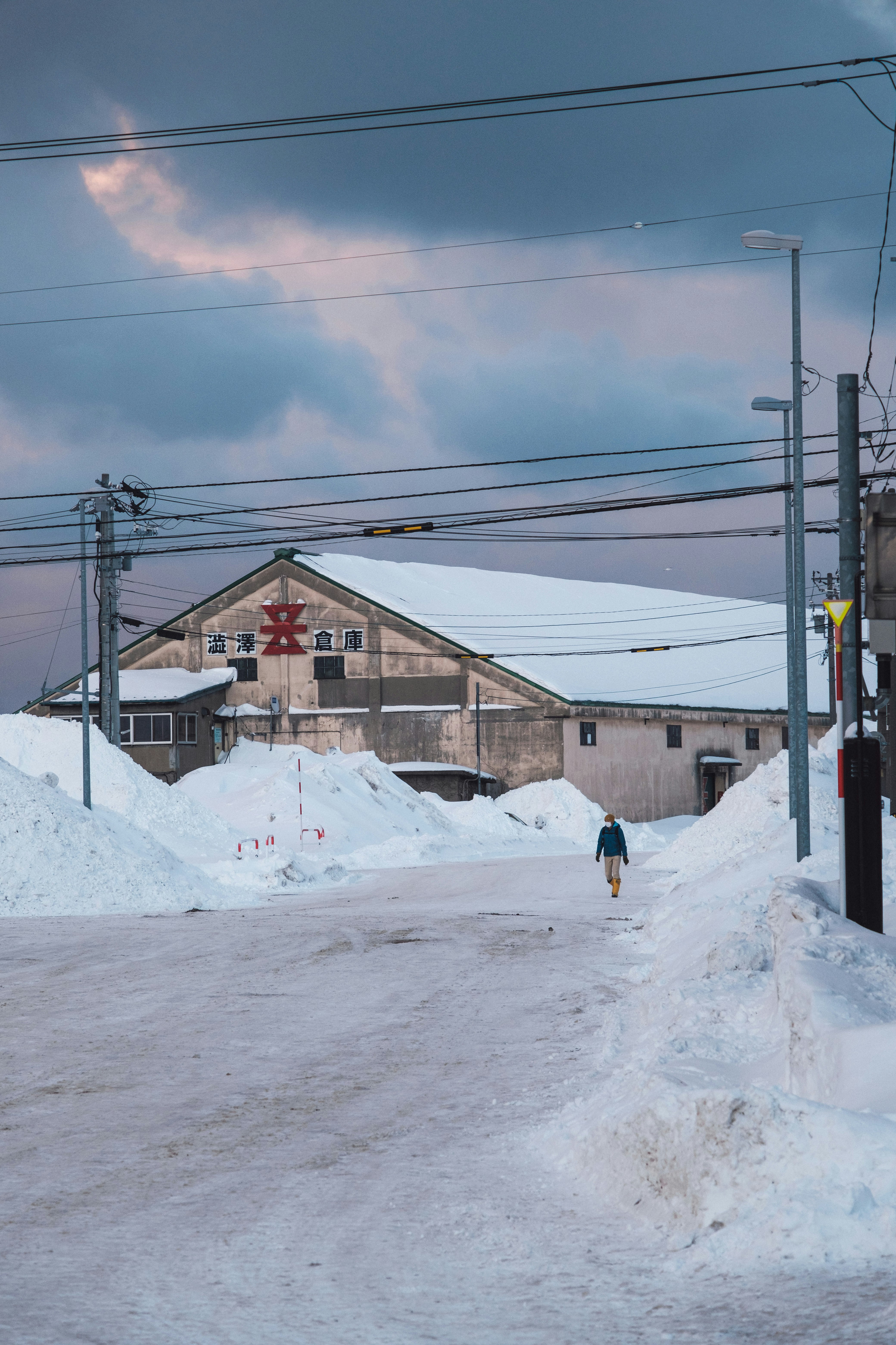 雪の積もる路地を歩く人と家並みのある冬景色
