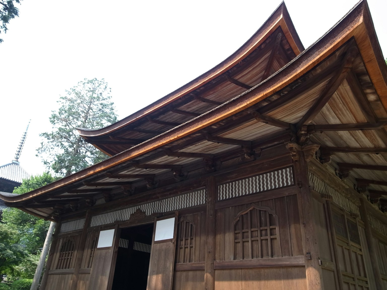 Exterior view of a traditional Japanese wooden temple with distinctive roof design