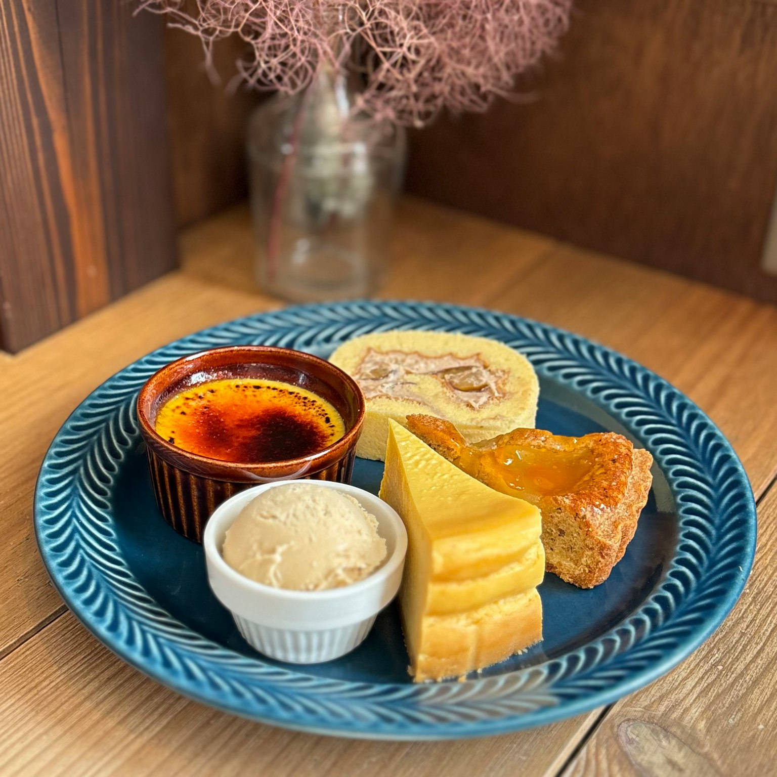Plato de postres en un plato azul con crème brûlée helado de vainilla tarta de frutas y galletas