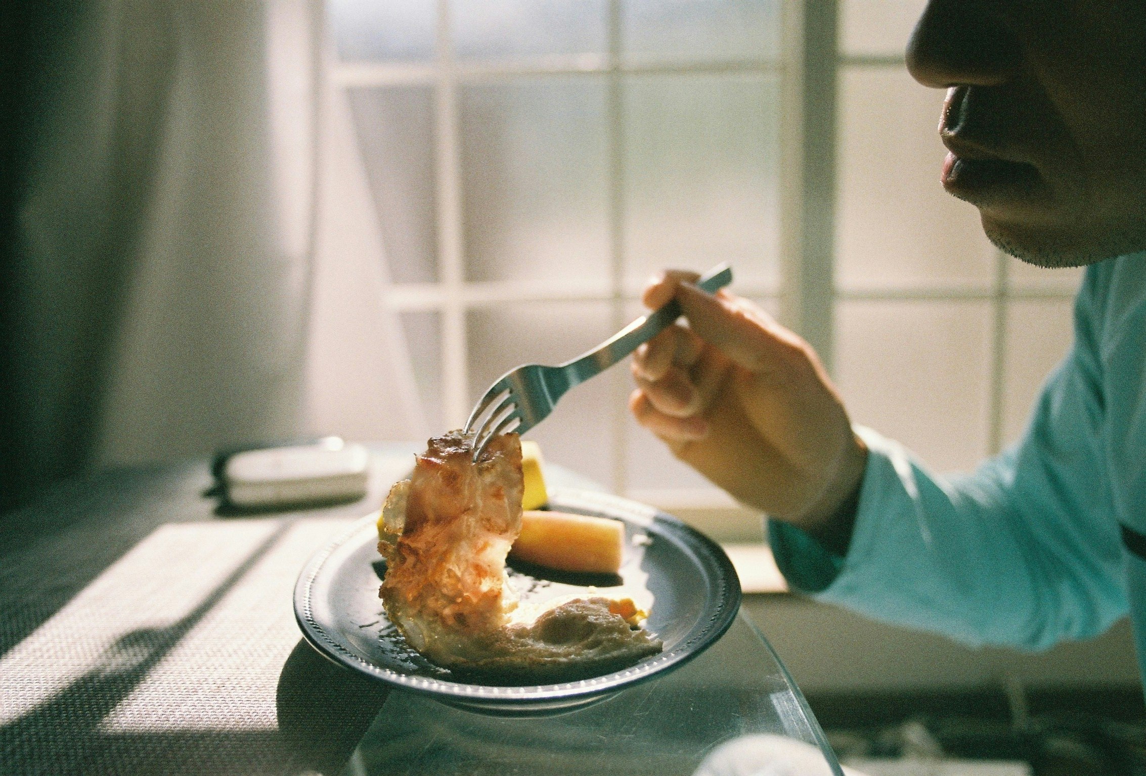 朝食のテーブルでパンを食べる人の横顔
