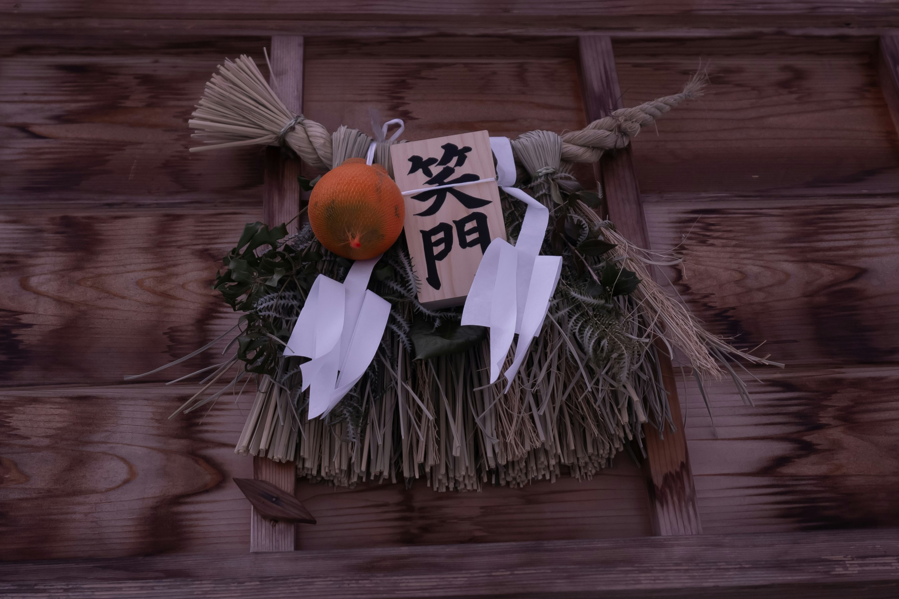Decoración de shimenawa y motivo tipo kagami-mochi en una puerta de madera