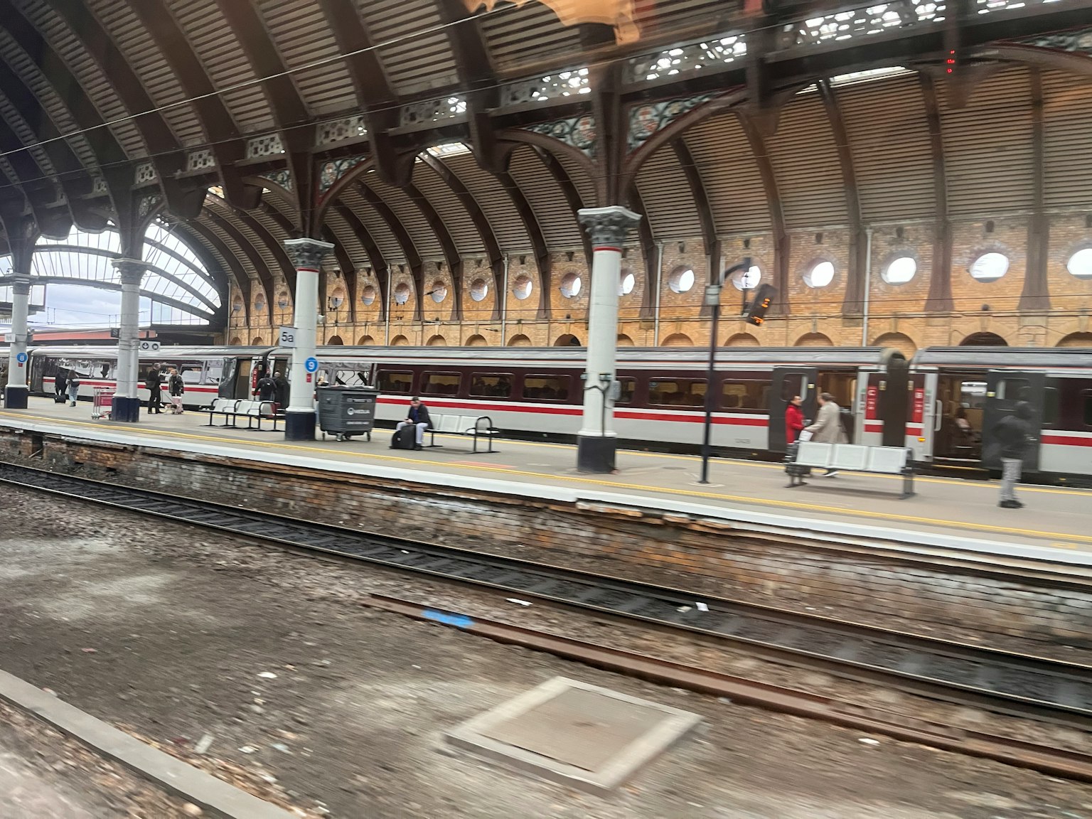 Treno su una banchina della stazione con passeggeri e dettagli architettonici unici