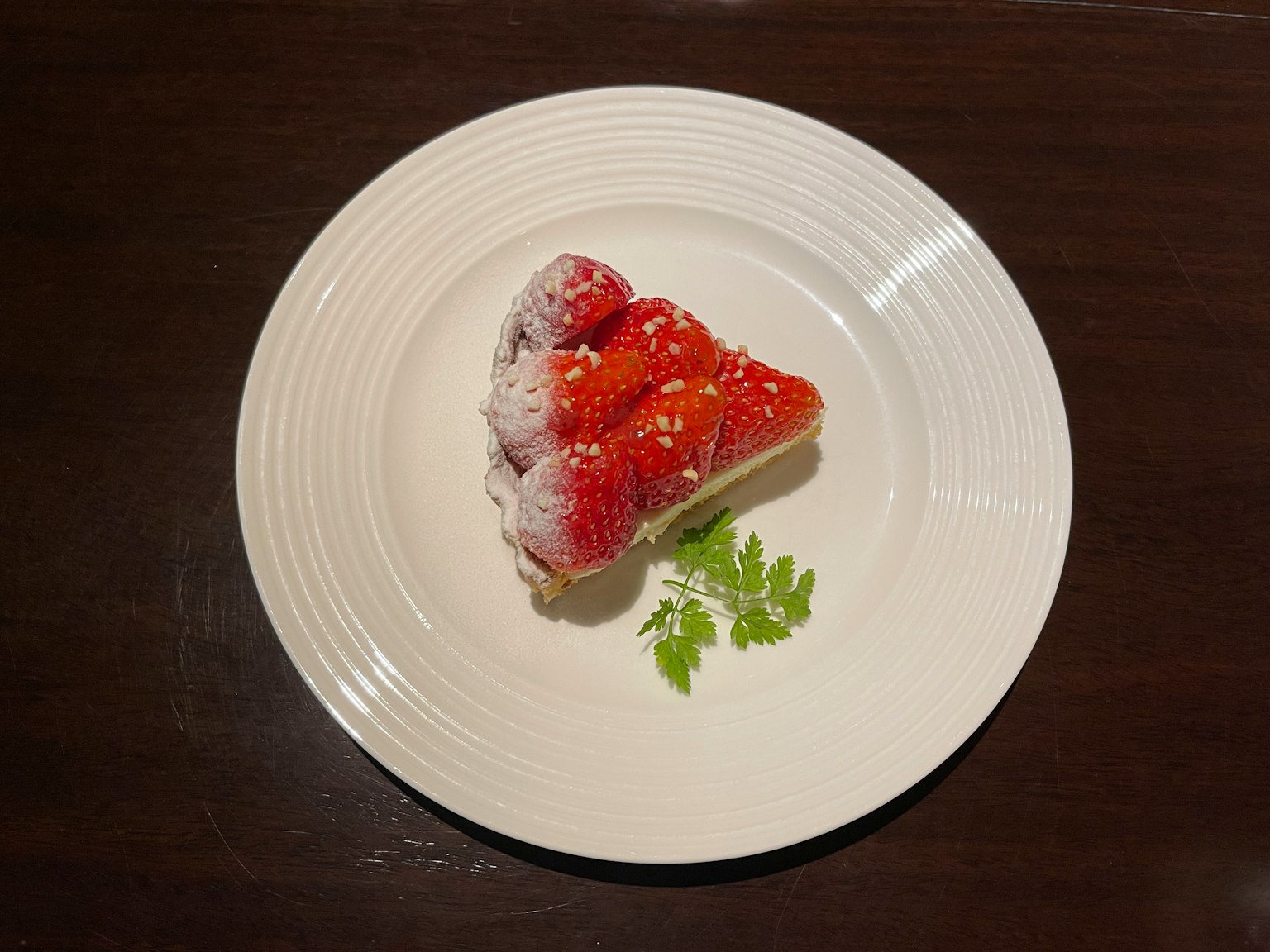 Un bellissimo dessert rosso guarnito con foglie verdi su un piatto bianco