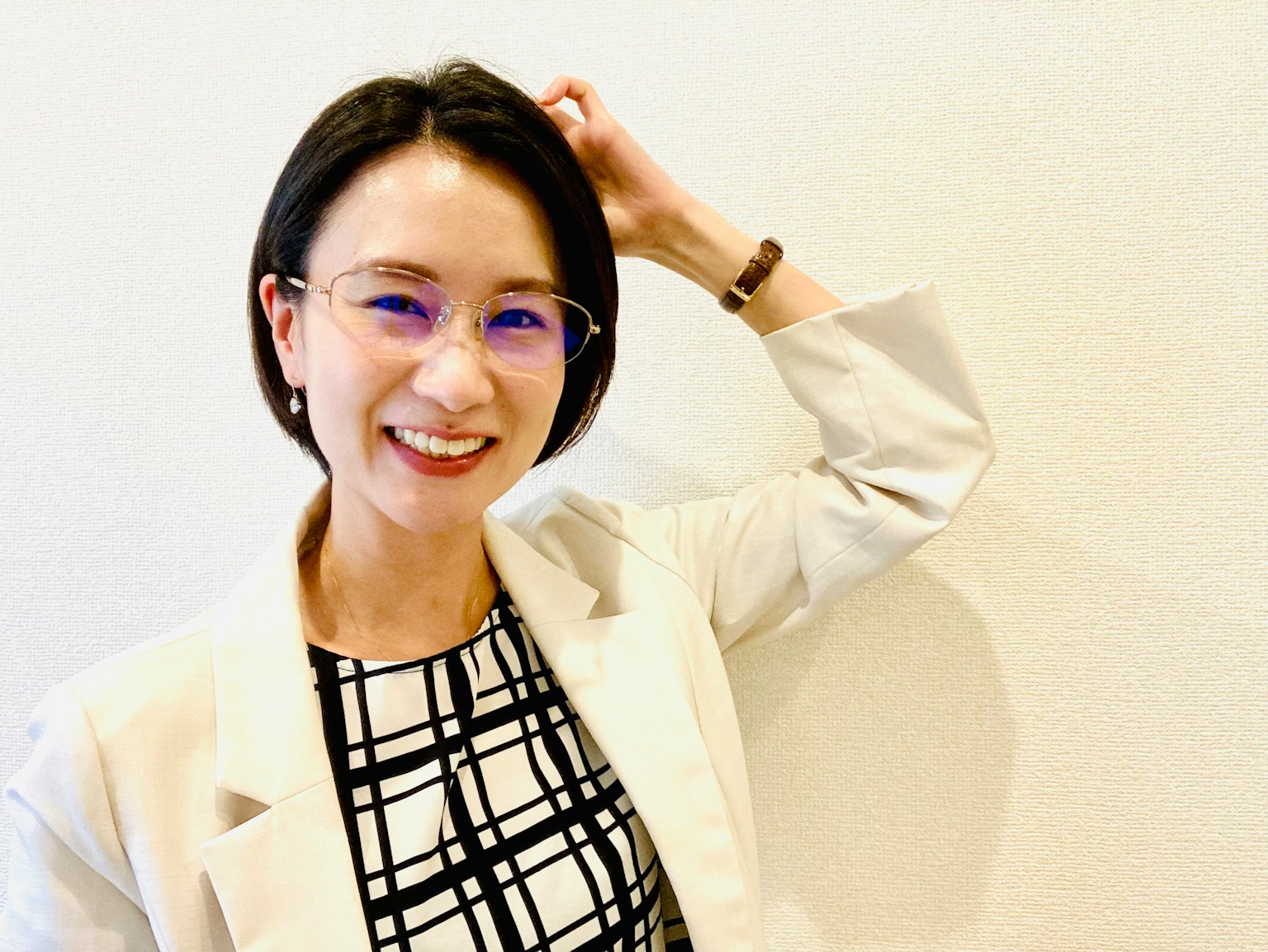 一位女性在白色牆壁前微笑著撫摸她的頭髮