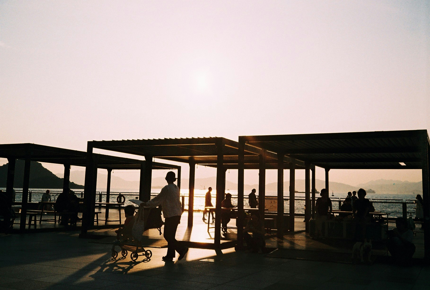 海辺の桟橋で人影がシルエットになった夕暮れの風景