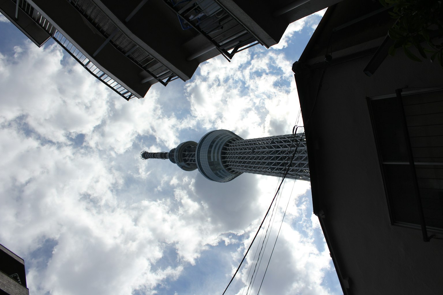 Tokyo Skytree towering against a cloudy sky in a narrow street
