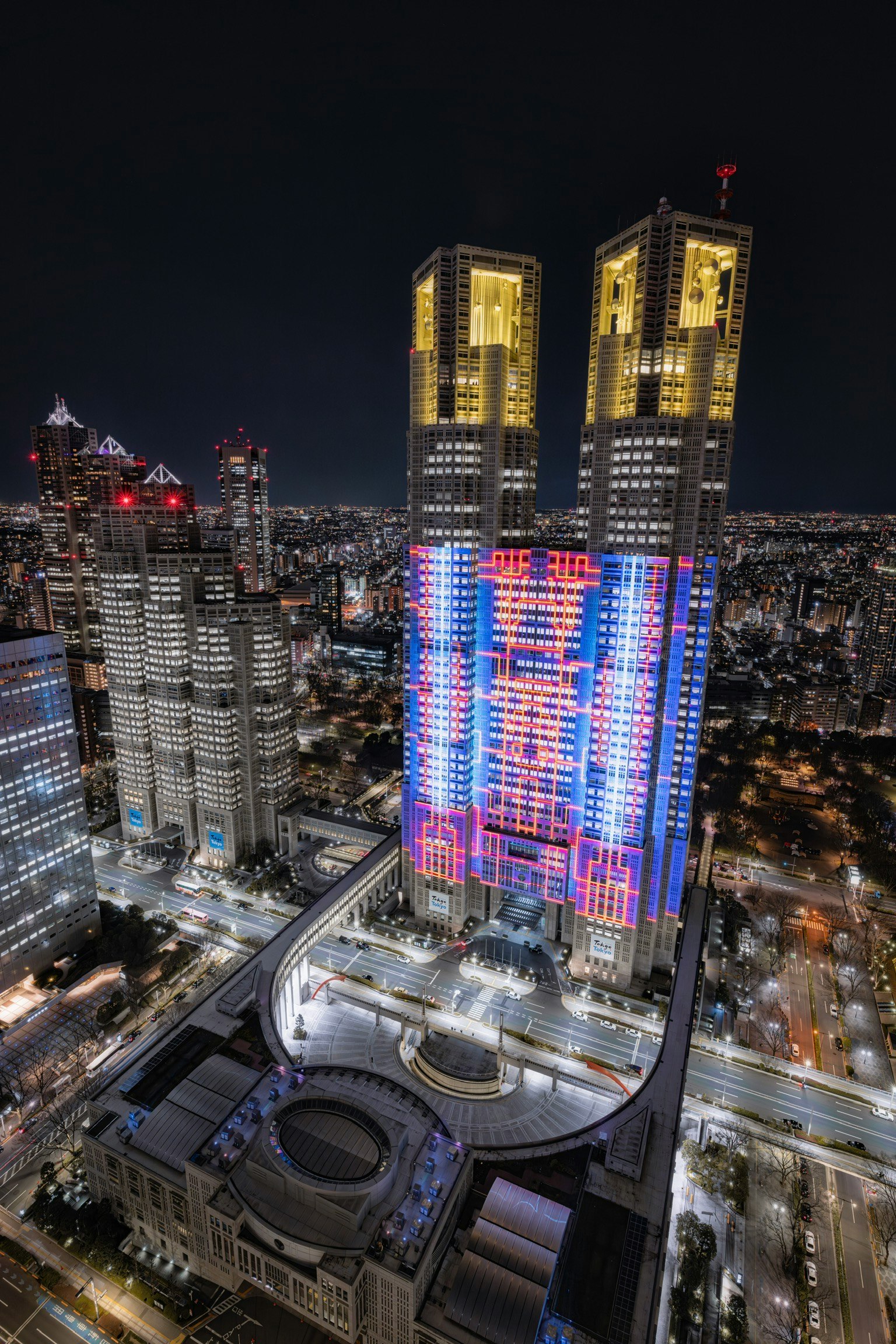 Gedung pemerintah metropolitan Tokyo yang diterangi di Shinjuku di malam hari dikelilingi oleh cakrawala kota