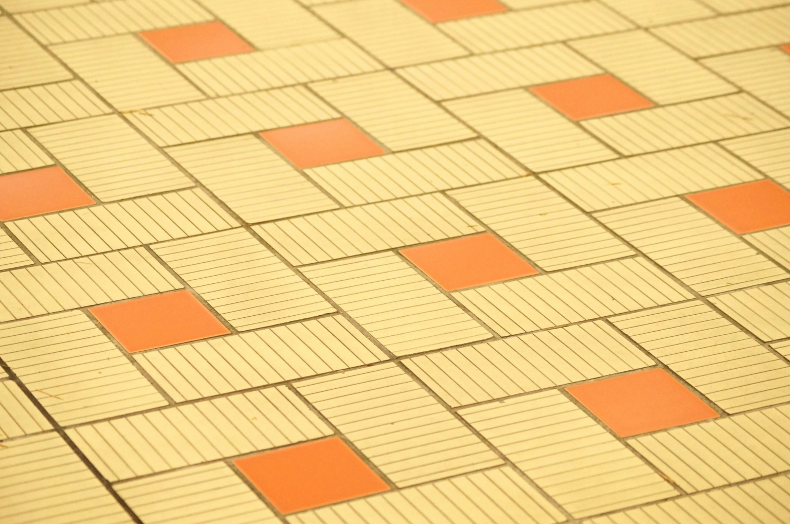 Bodenfliesen mit geometrischem Muster und orangefarbenen Quadraten
