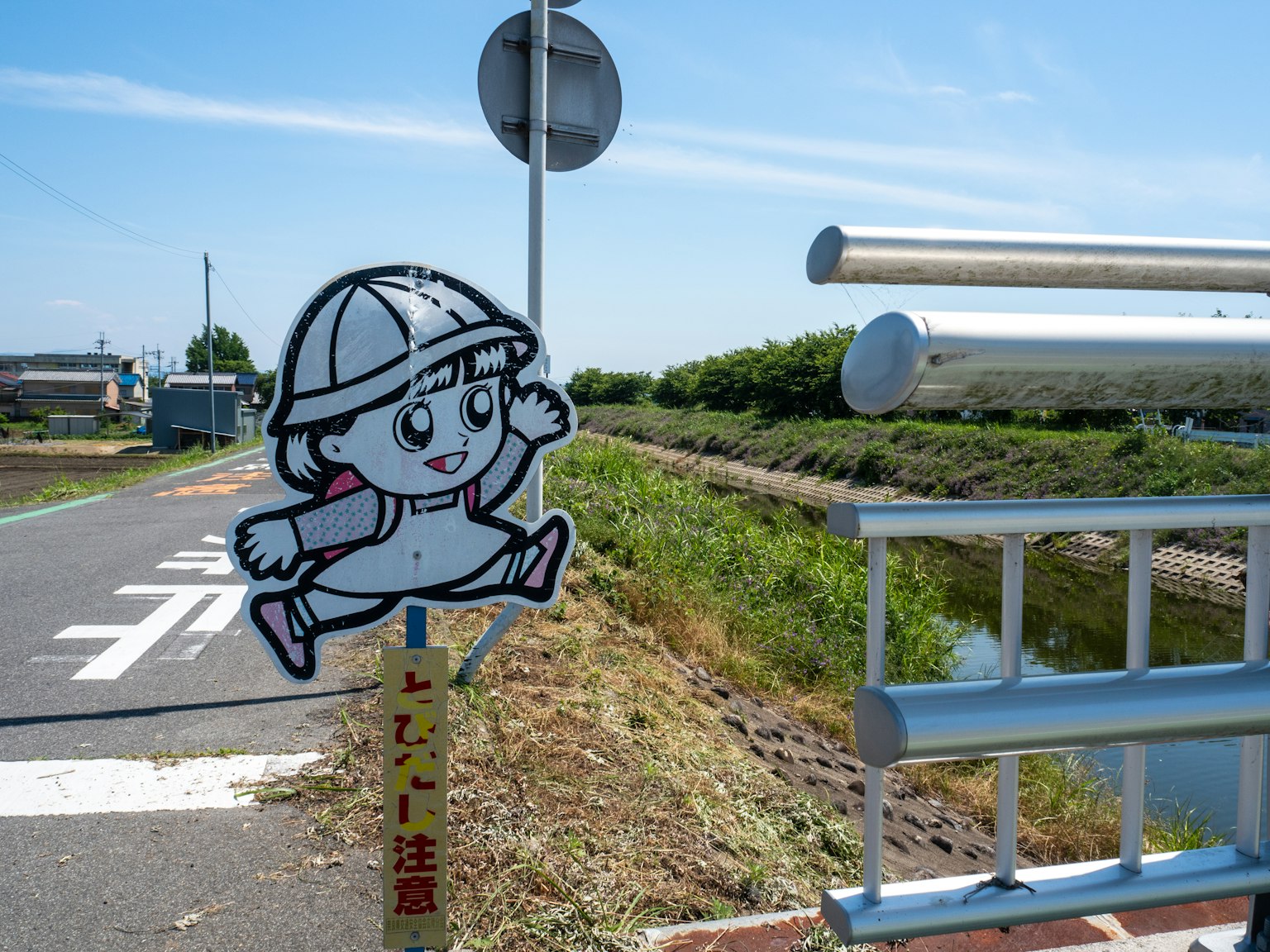 Un panneau avec un personnage d'enfant près d'une berge Ciel bleu clair et paysage verdoyant
