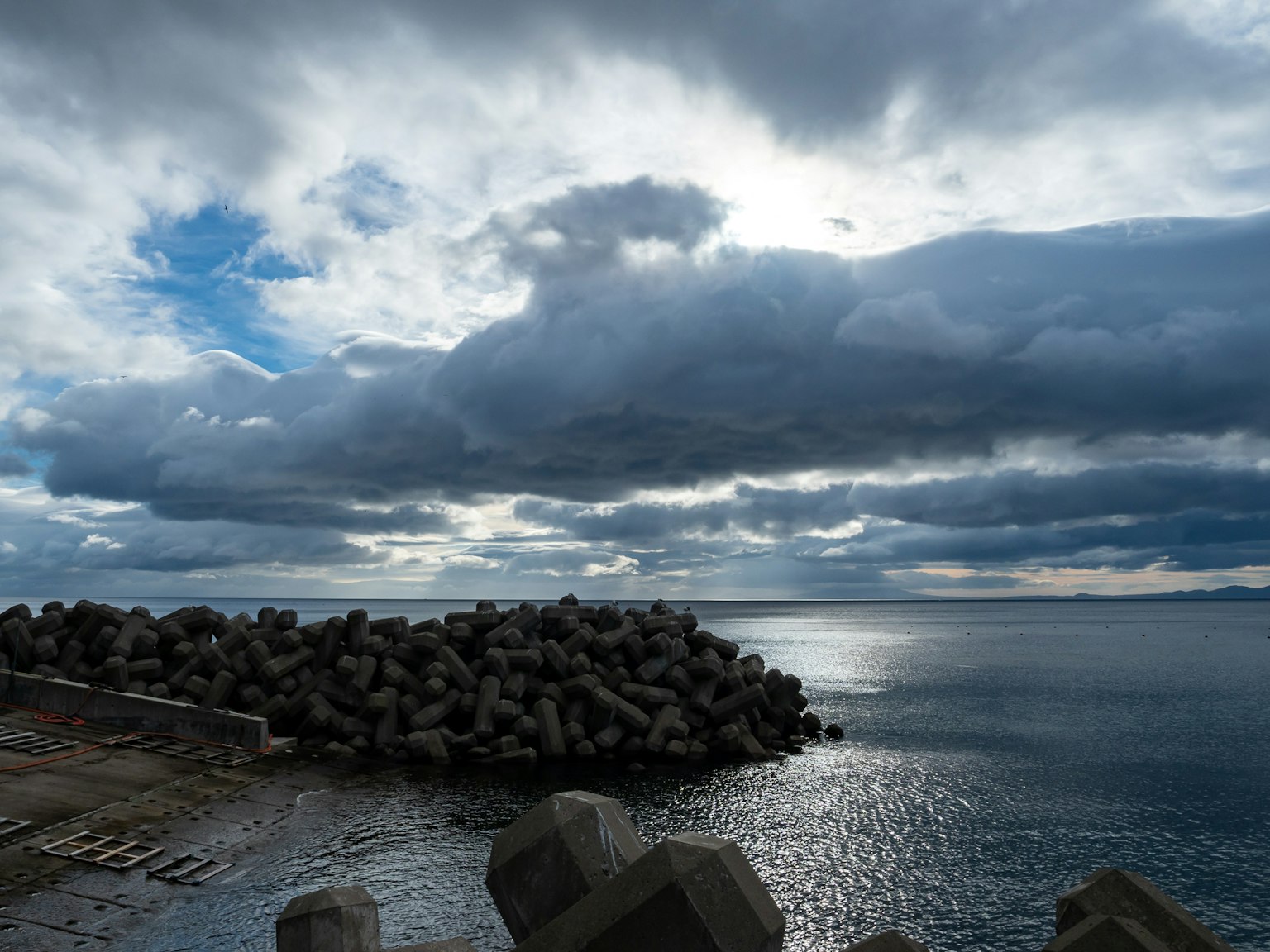 Vista sul mare con un molo e cielo nuvoloso