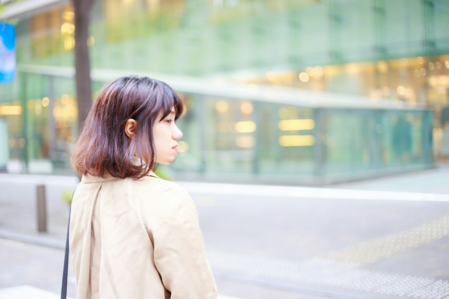 一名女性在街上走,背景是模糊的玻璃建築