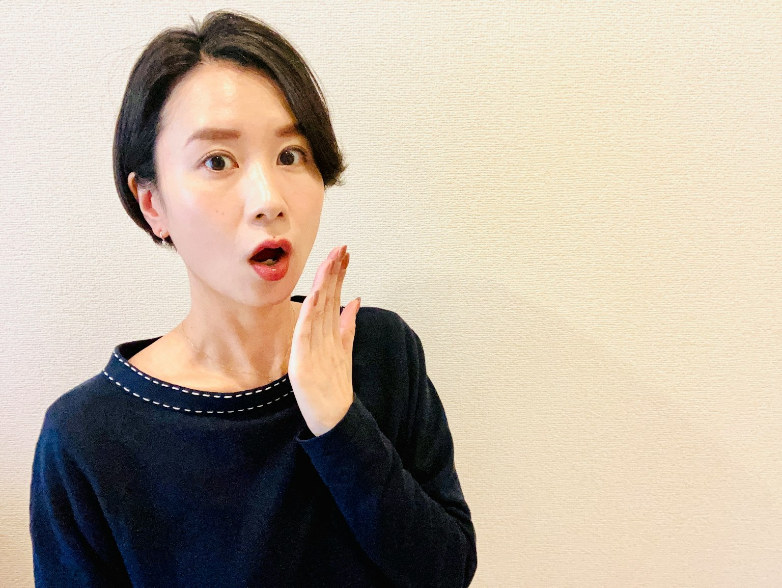 Một người phụ nữ với biểu cảm ngạc nhiên đang che miệng bằng tay