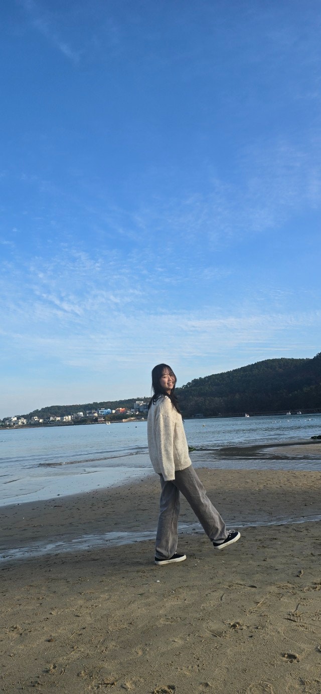 海辺の砂浜で歩く人物と広がる青空