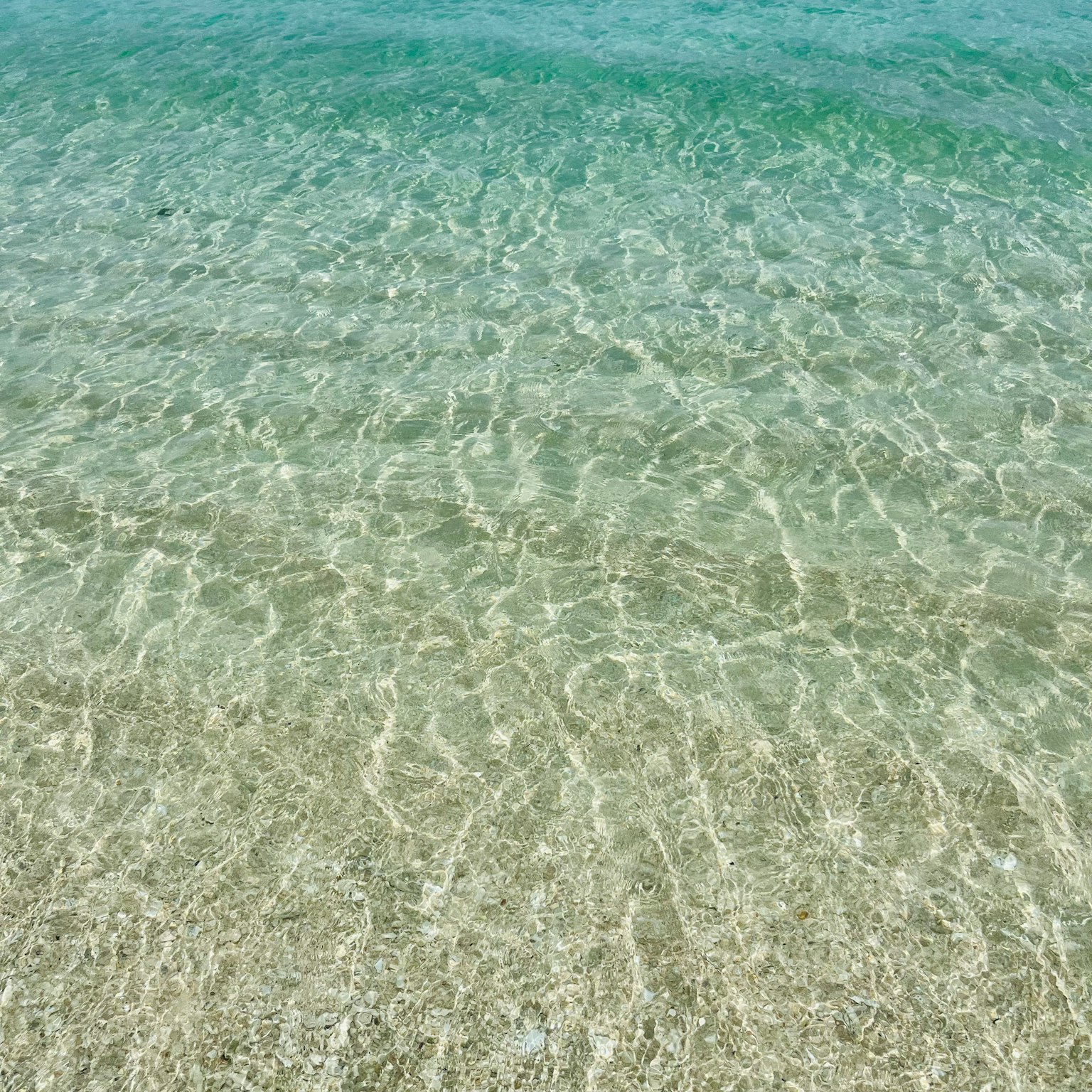 น้ำใสเหนือชายหาดทรายพร้อมคลื่นนุ่มนวล