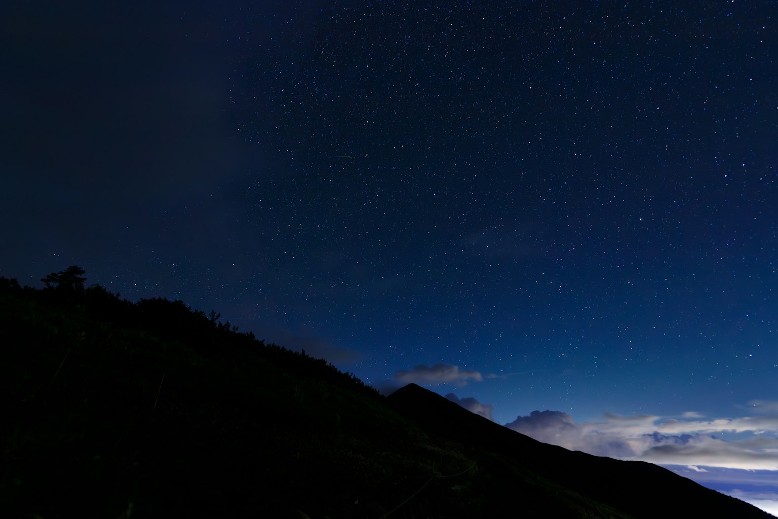 Night landscape featuring a starry sky and mountain silhouette