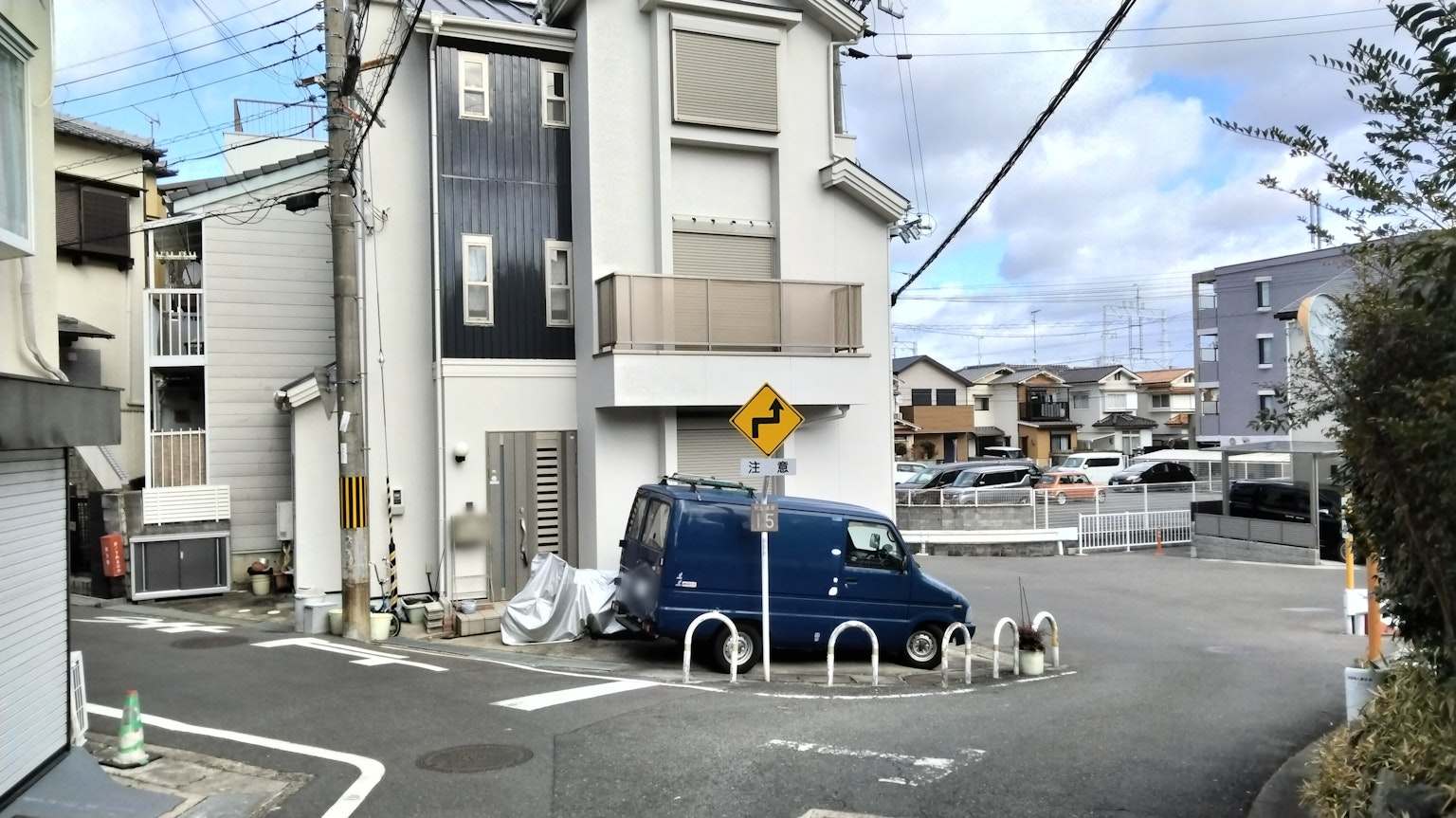 Un bâtiment moderne à un coin de rue avec un véhicule bleu garé à proximité