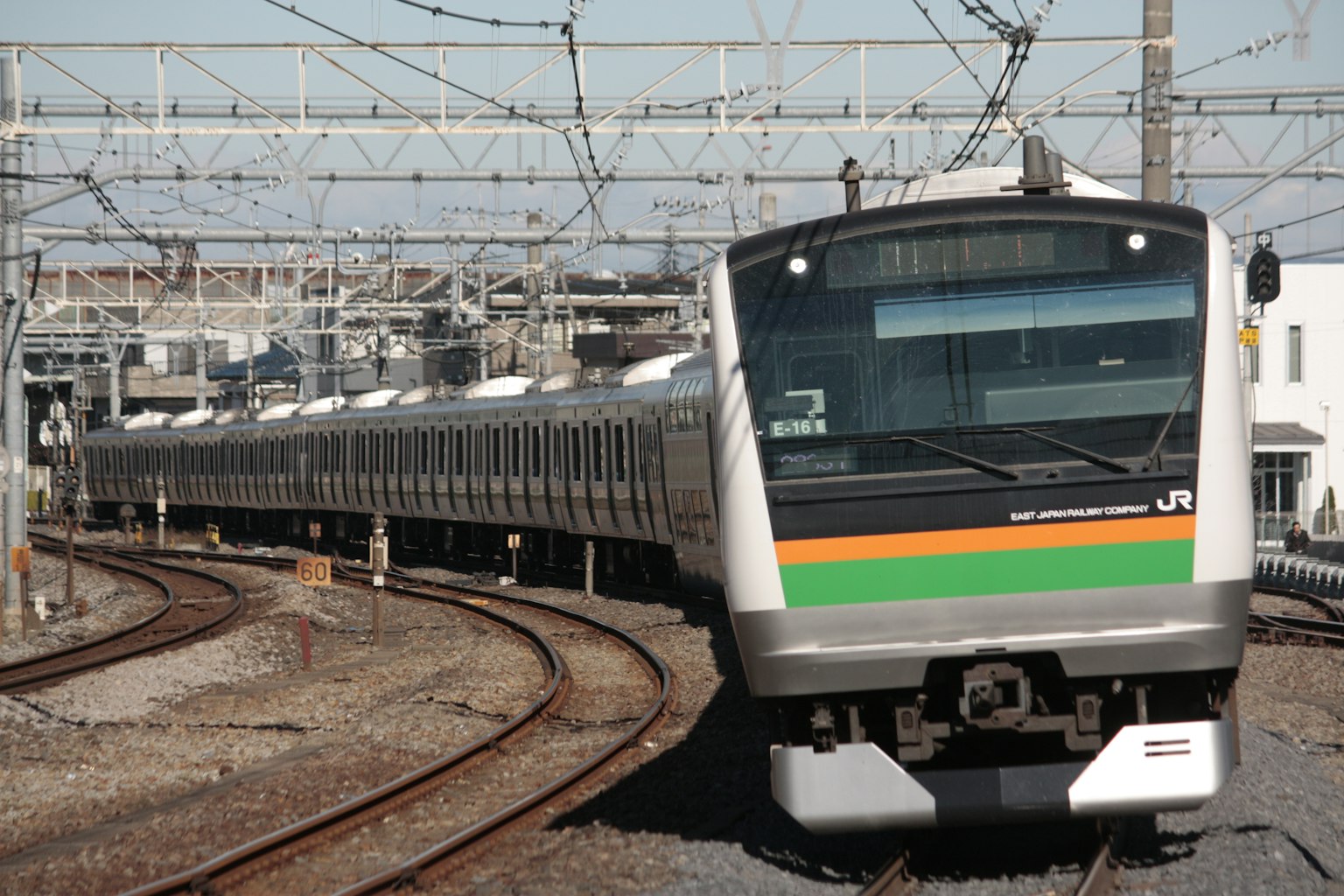 一列帶有橙色和綠色條紋的日本列車在彎曲的軌道上行駛
