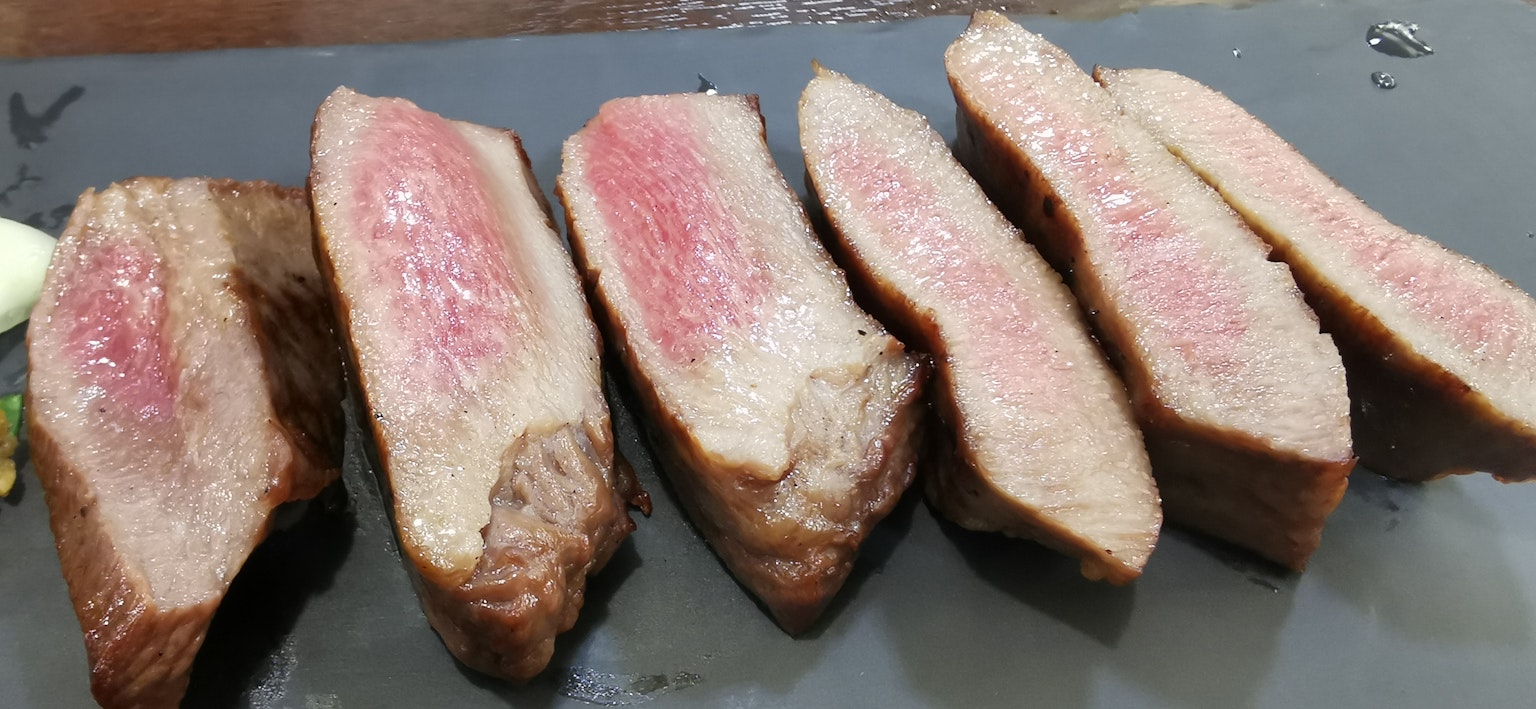 Sliced beef arranged on a black plate