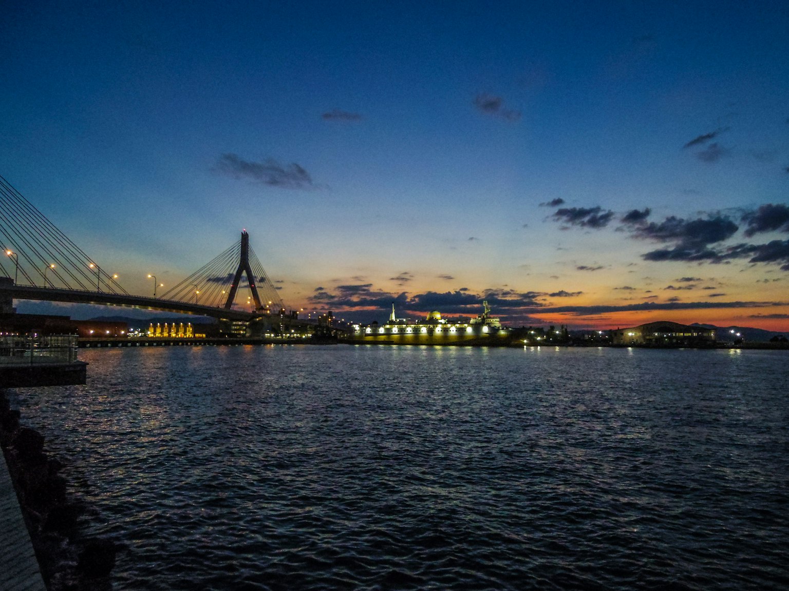 Silhouette di un ponte e edifici riflessi sull'acqua al crepuscolo
