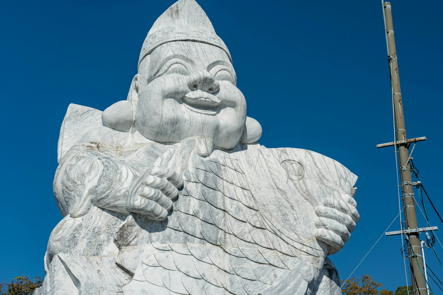 Grande statue blanche souriante tenant quelque chose dans les mains