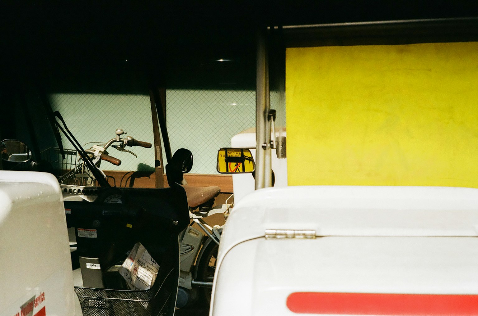 Industrial scene featuring a yellow wall and white vehicles