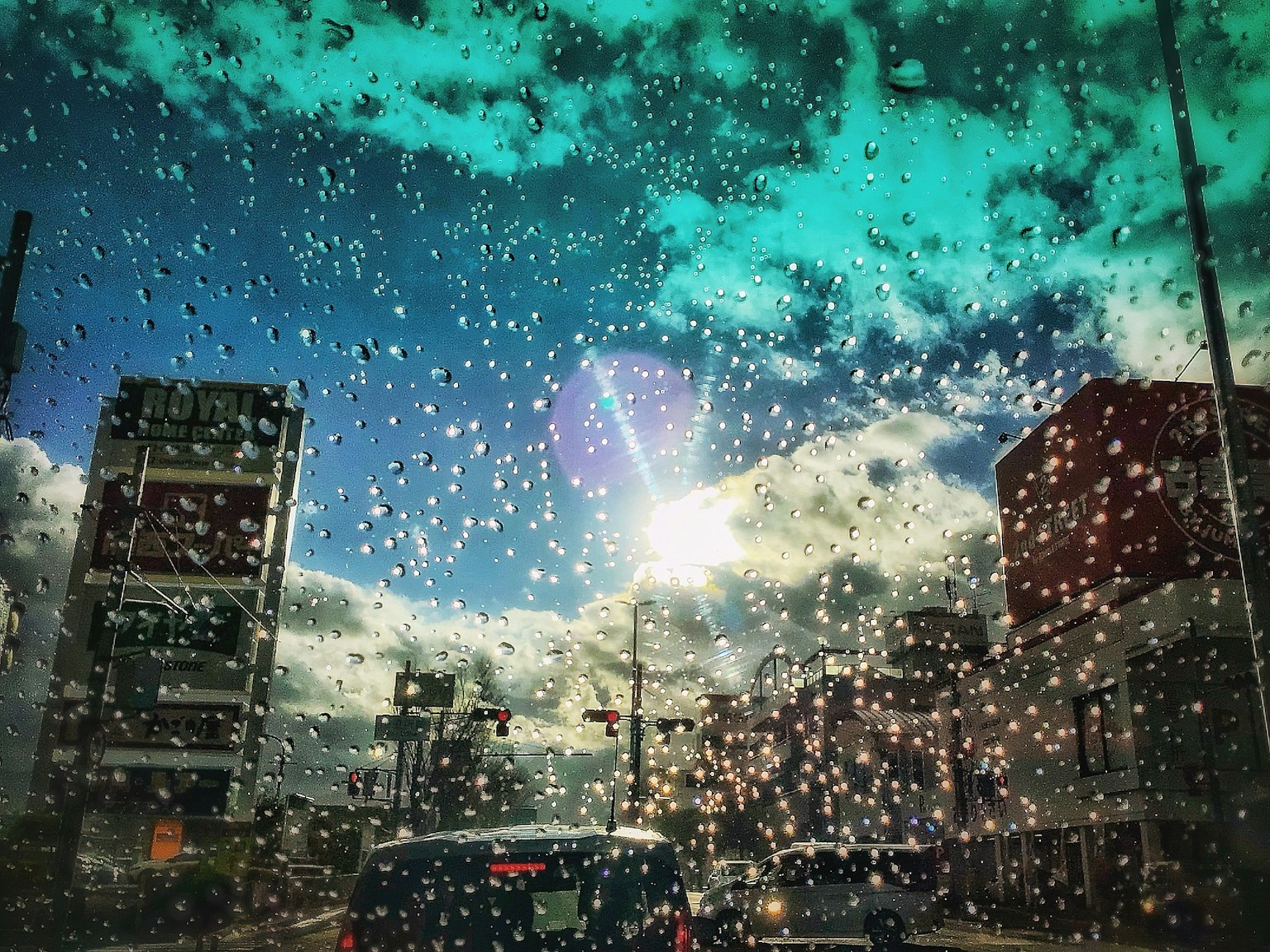 Paysage urbain vu à travers une fenêtre mouillée avec un soleil brillant