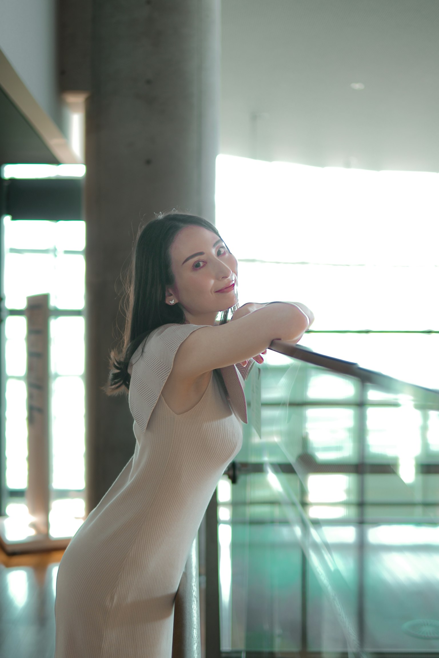 Woman in a slim dress posing in a modern building interior