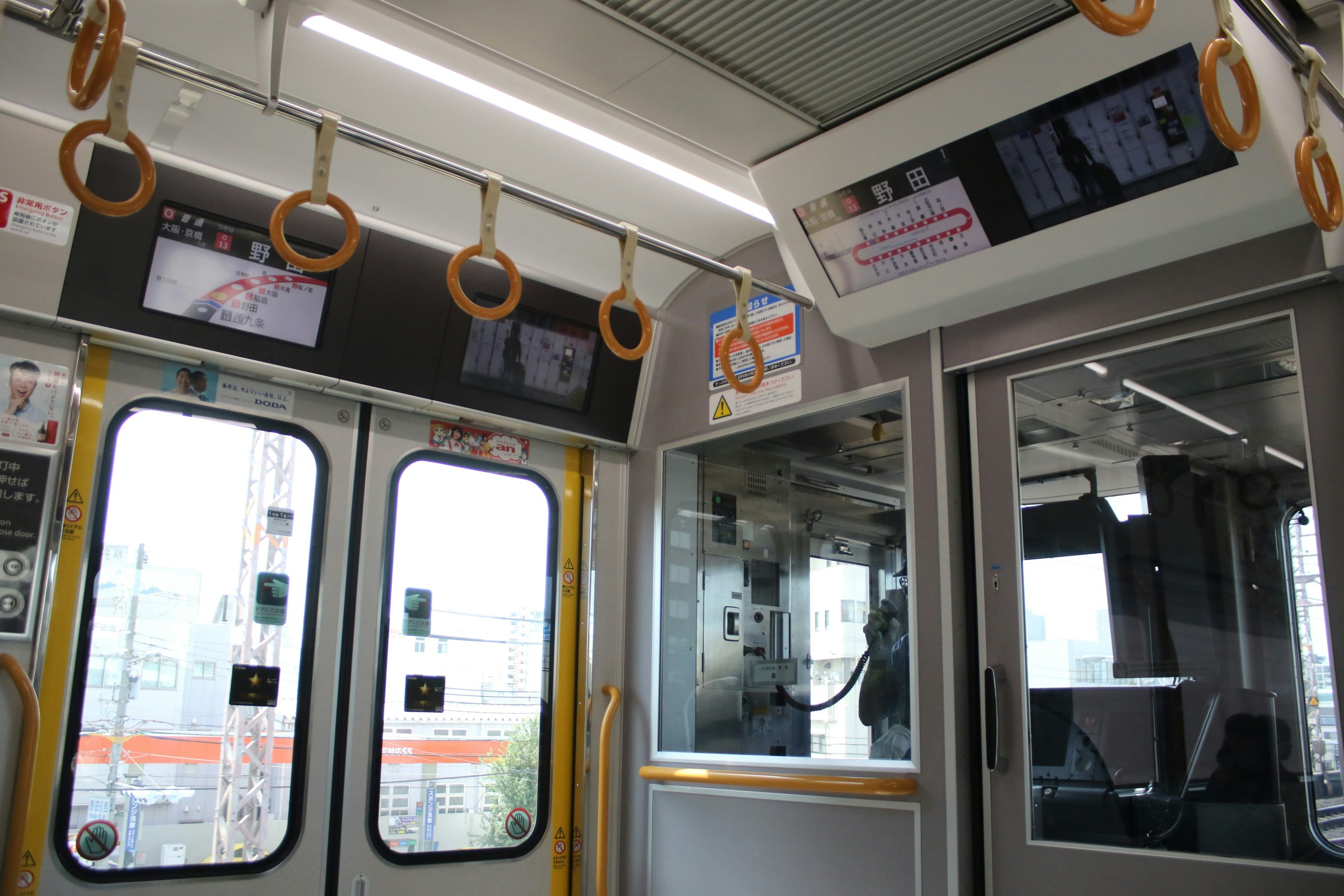 車内の手すりと路線表示が見える電車の内装