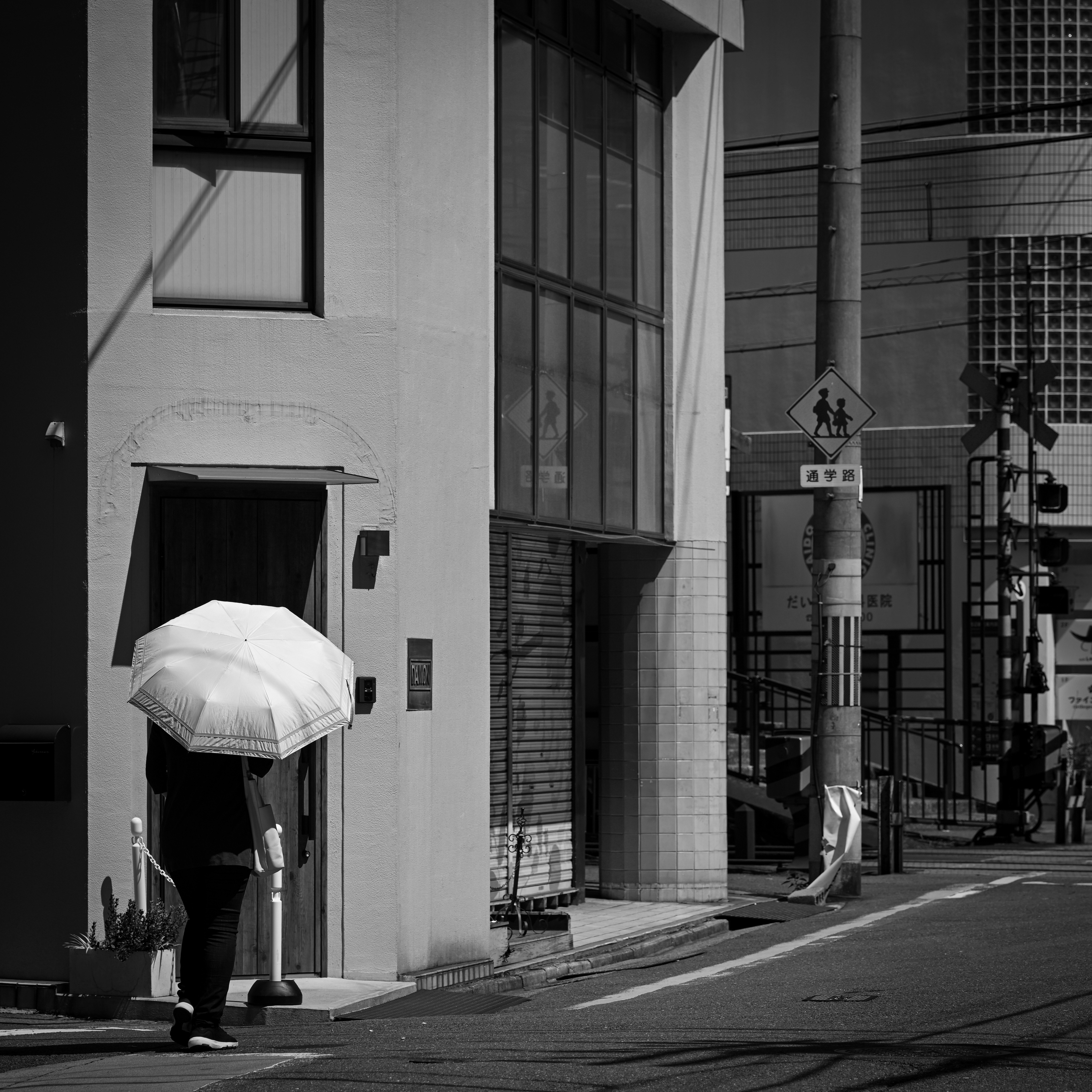 京都の路地で日傘をさす後ろ姿の人物