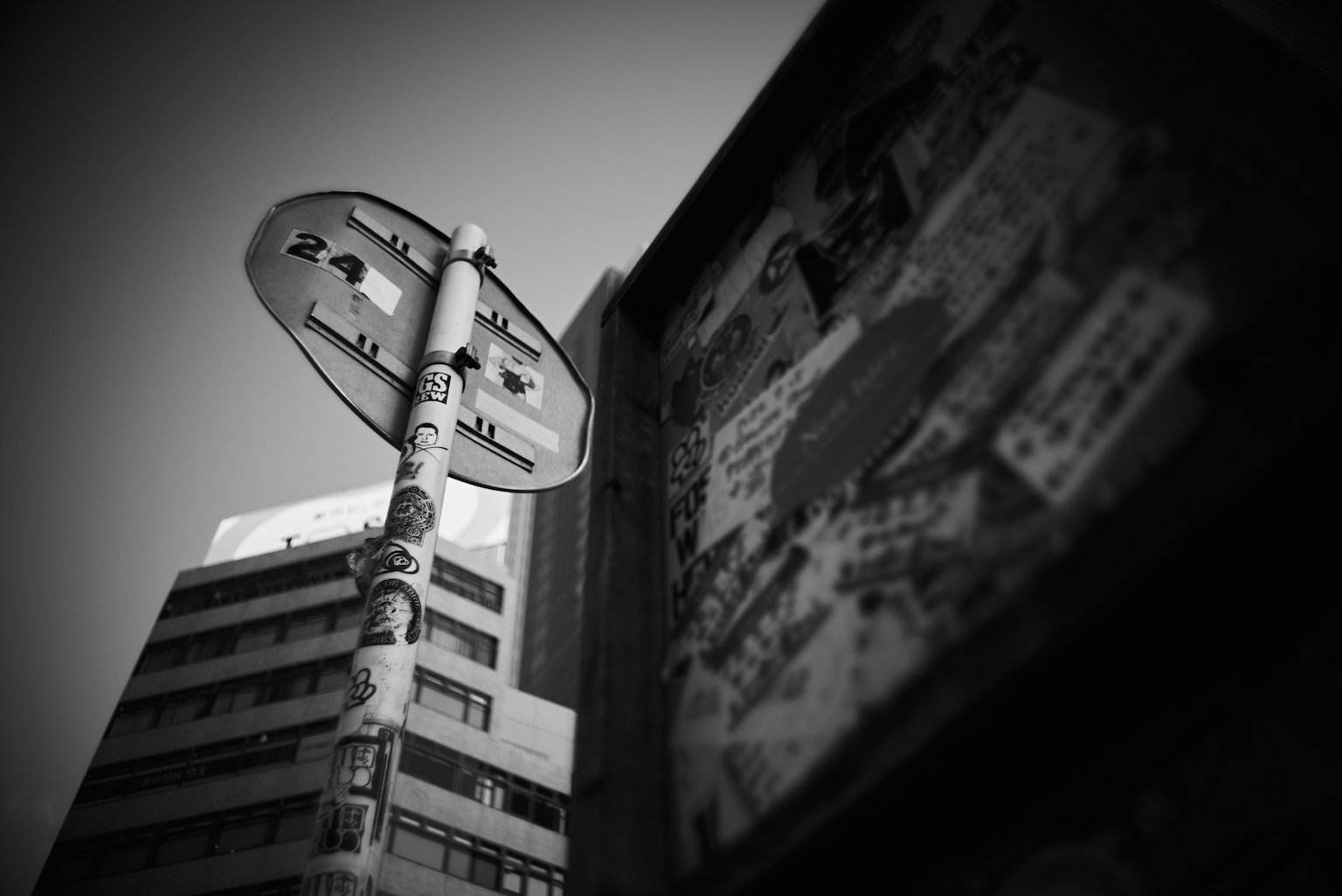 Paesaggio urbano in bianco e nero con un cartello di fermata dell'autobus e pubblicità