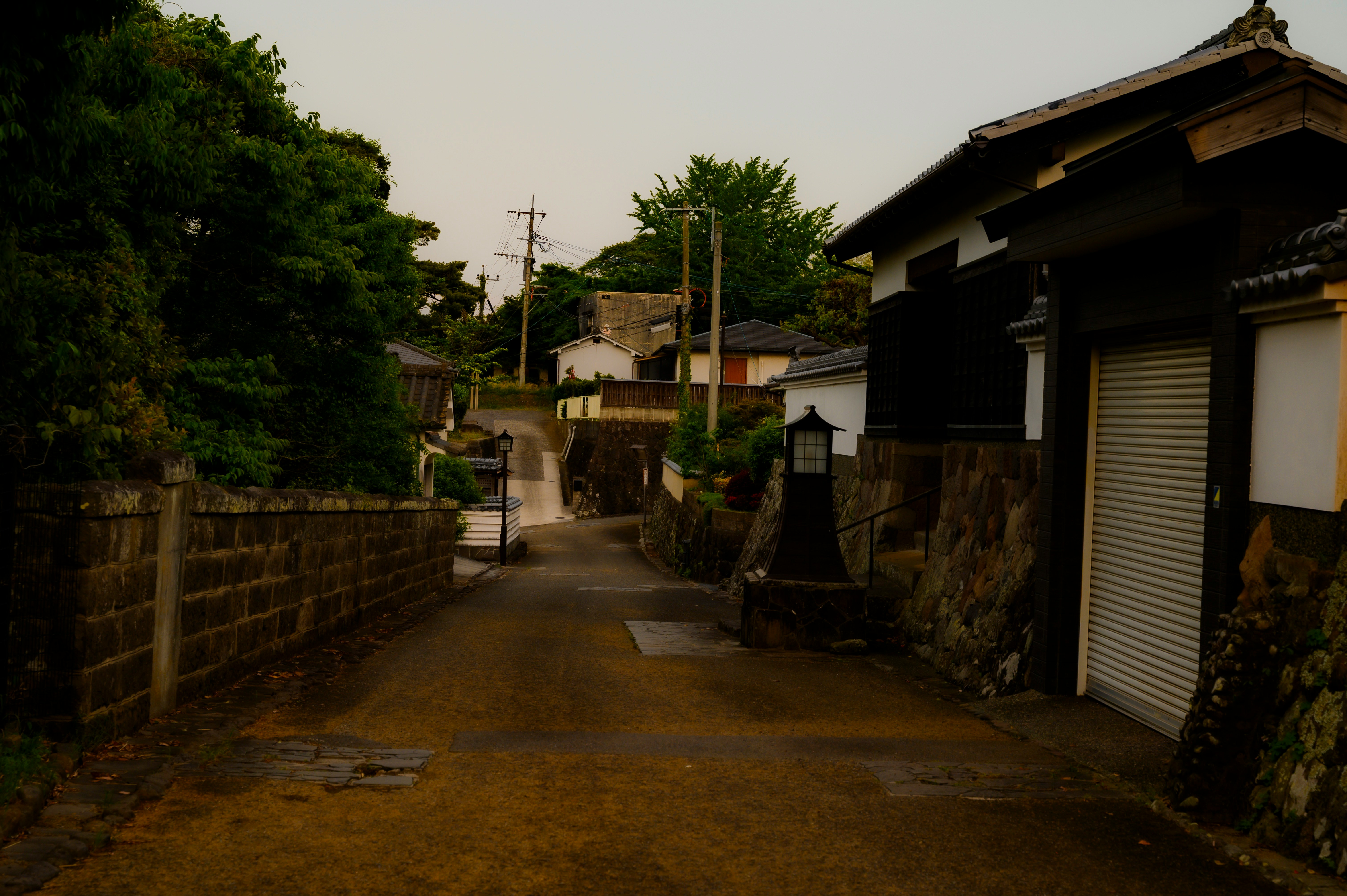 塀と軒先が続く静かな路地の夕暮れ風景