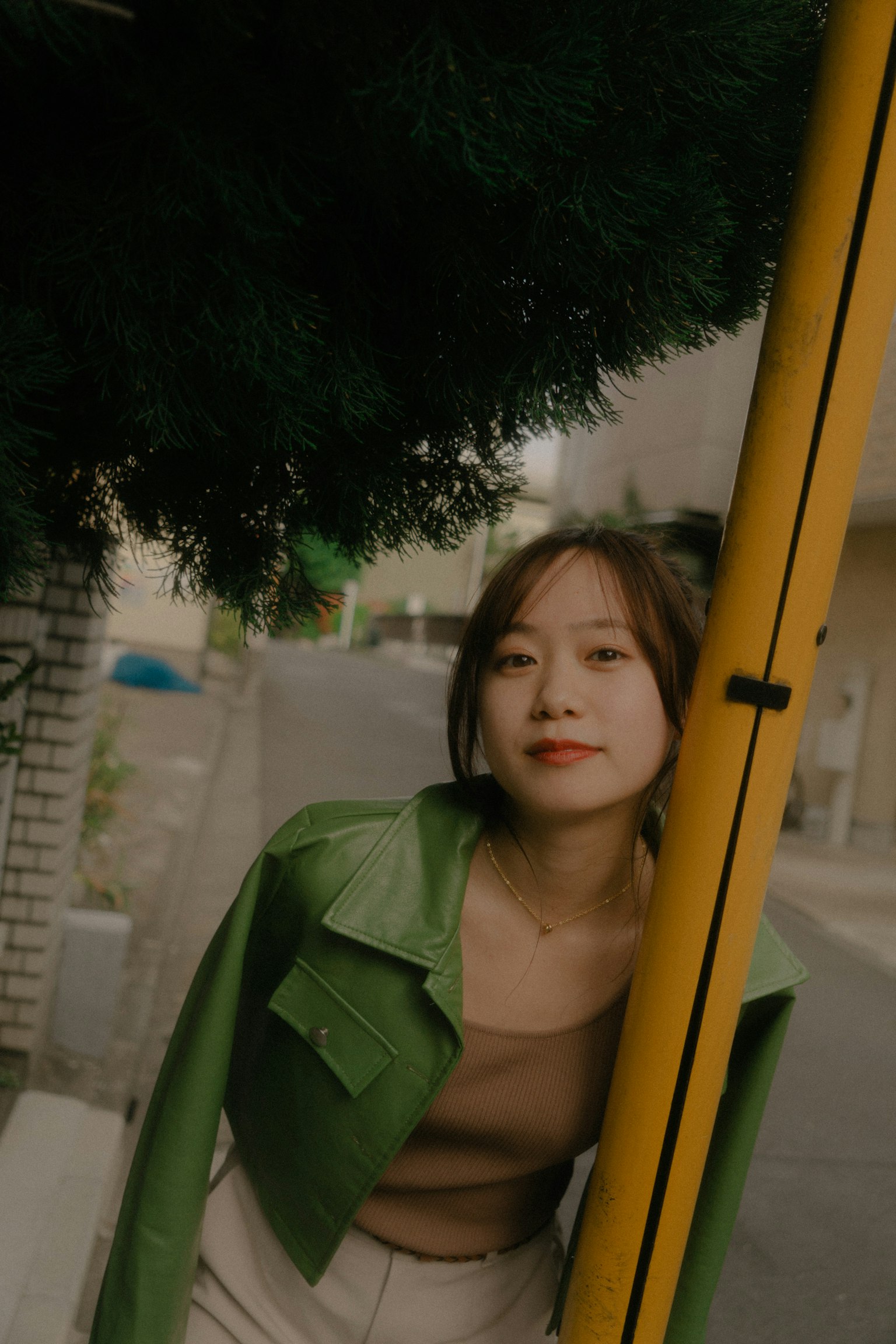 Une femme portant une veste verte posant dans la rue