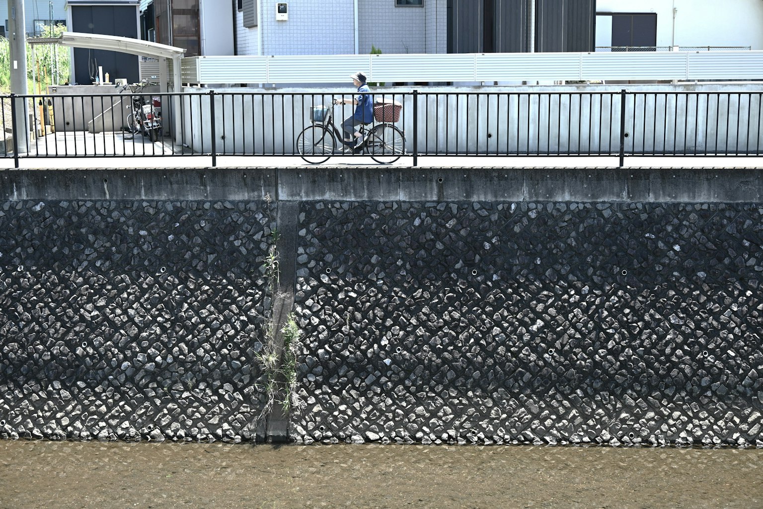 Une personne à vélo le long d'un mur en béton au bord d'un cours d'eau