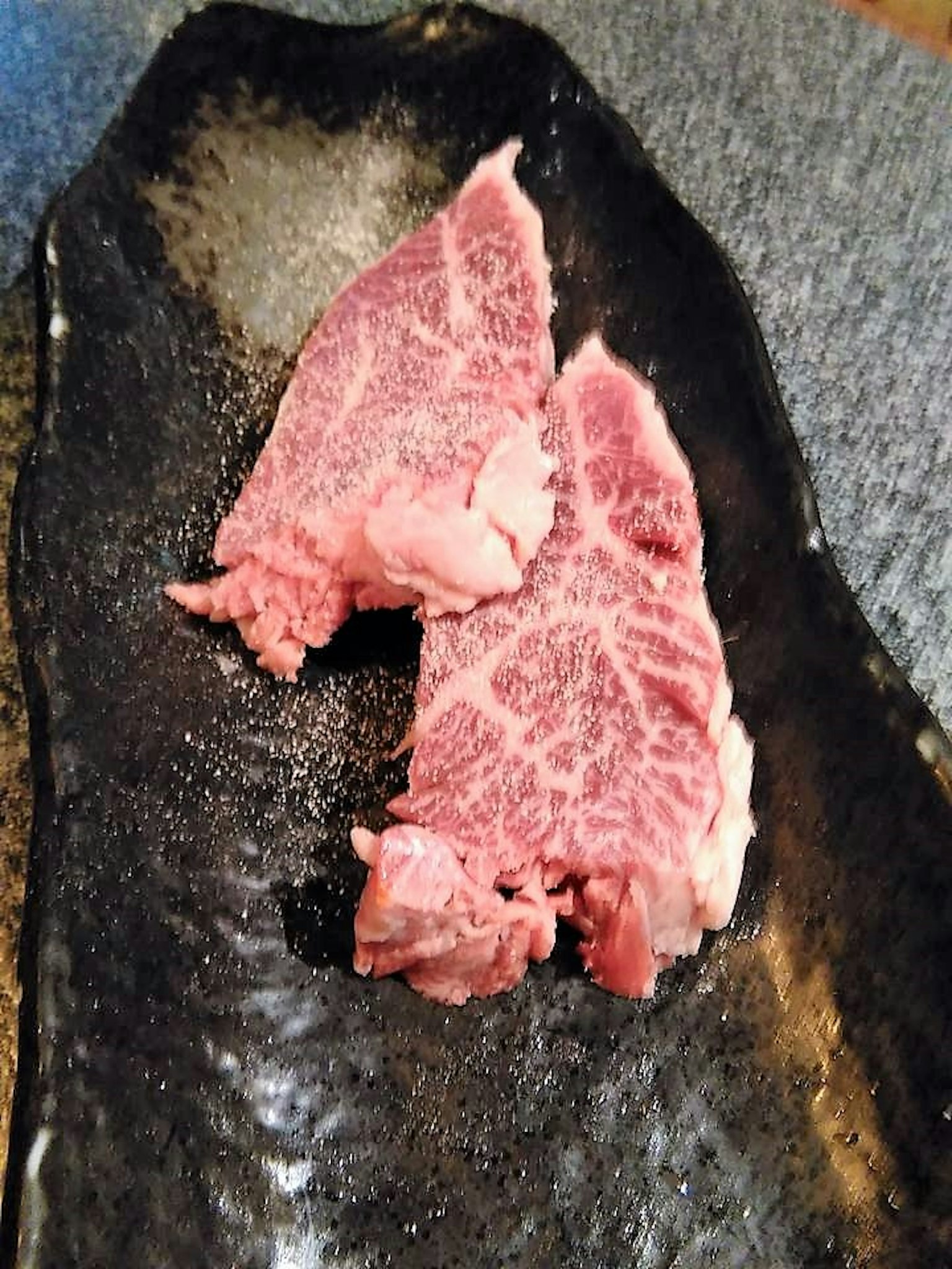 검은 접시 위에 놓인 두 개의 마블링 쇠고기 스테이크