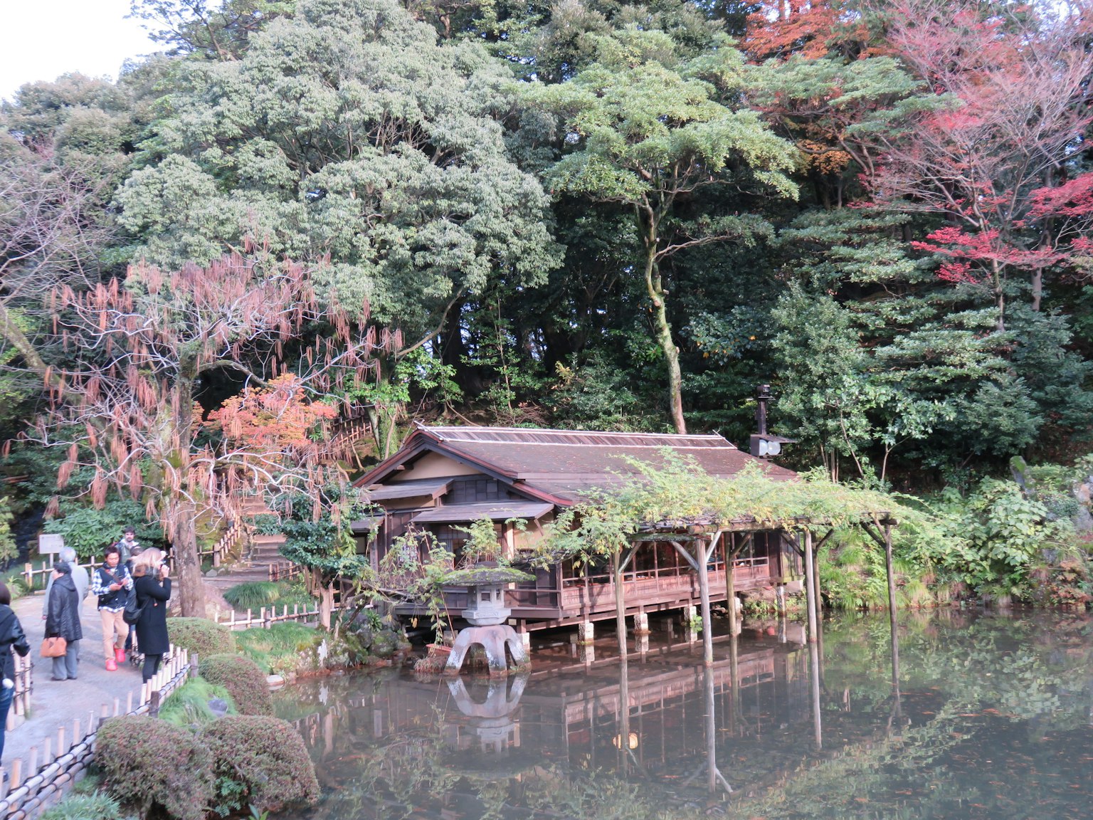 Hutte japonaise traditionnelle au bord d'un étang serein entourée de verdure luxuriante